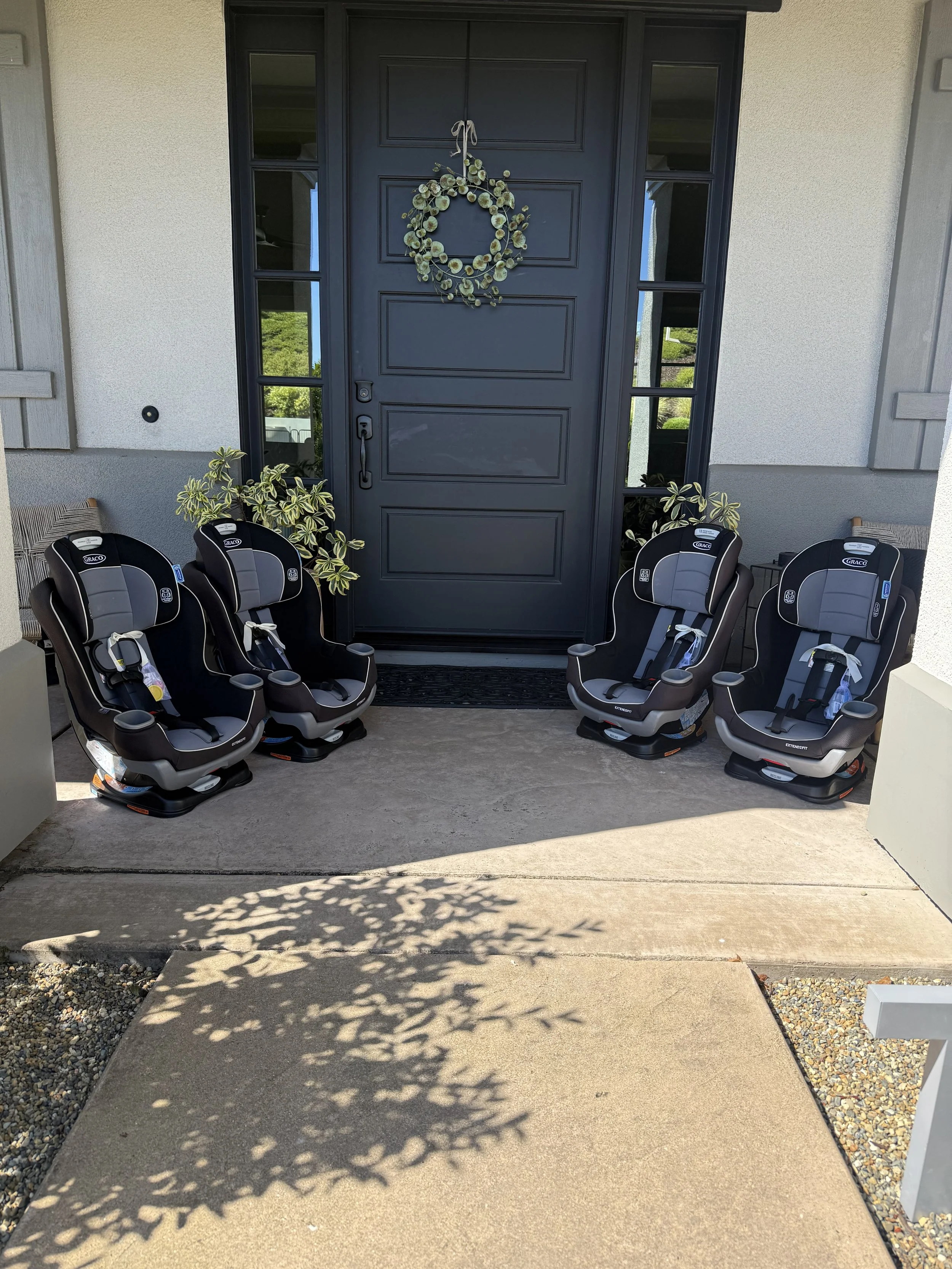 Front porch of a house with four car seats lined up in front of the front door.