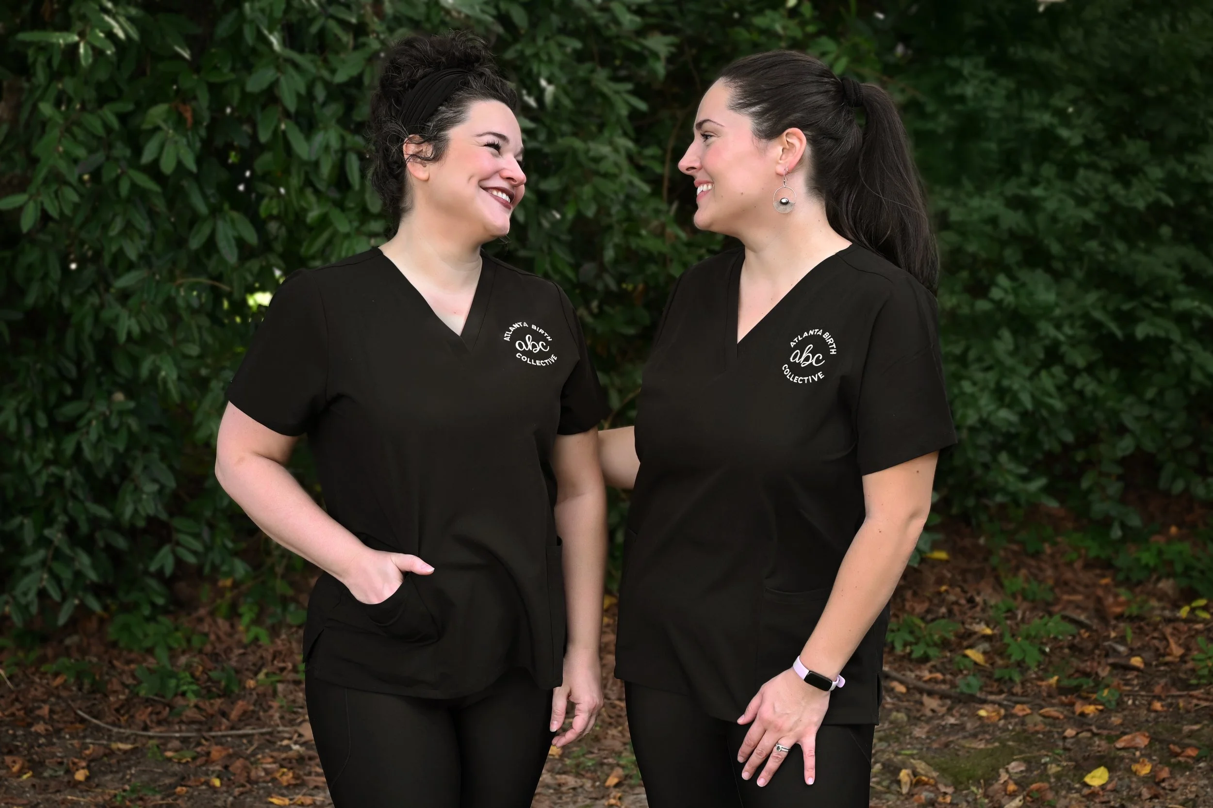 Professional portrait of Atlanta Birth Collective doulas Milene and Maegan, wearing black uniforms with the ABC logo, providing expert birth and postpartum support throughout North Atlanta, Woodstock, Roswell, Alpharetta and Canton.