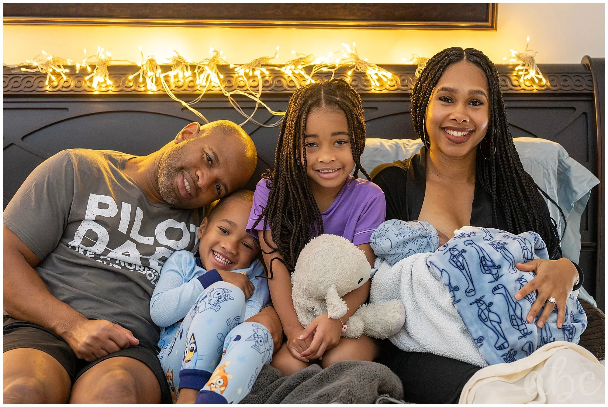 Family cuddles in bed after home birth and is enjoying new baby.