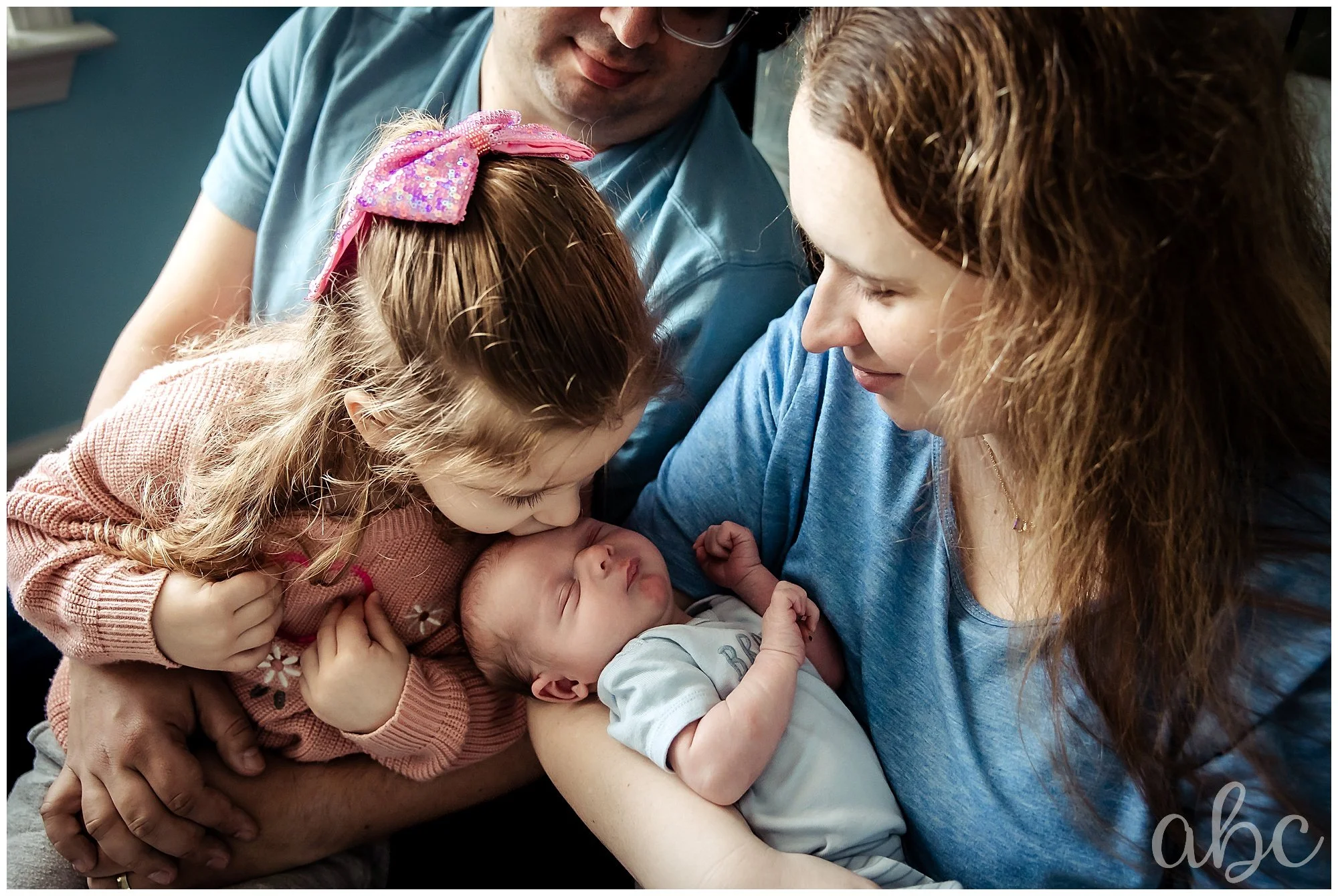 Mom and dad hold and cuddle their children at the newborn shoot with Woodstock doula photographer Milene Miller