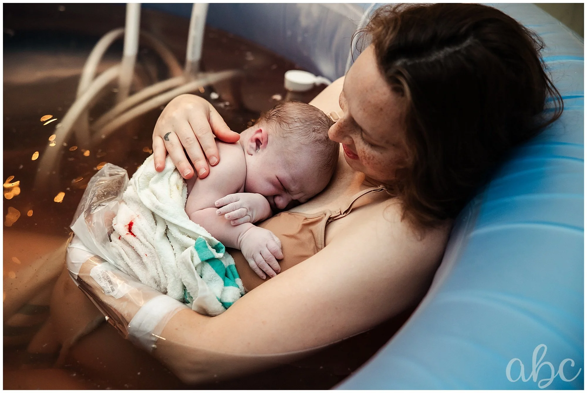 Mom cuddles her new baby in the birth tub as Woodstock Doula Photographer takes photos