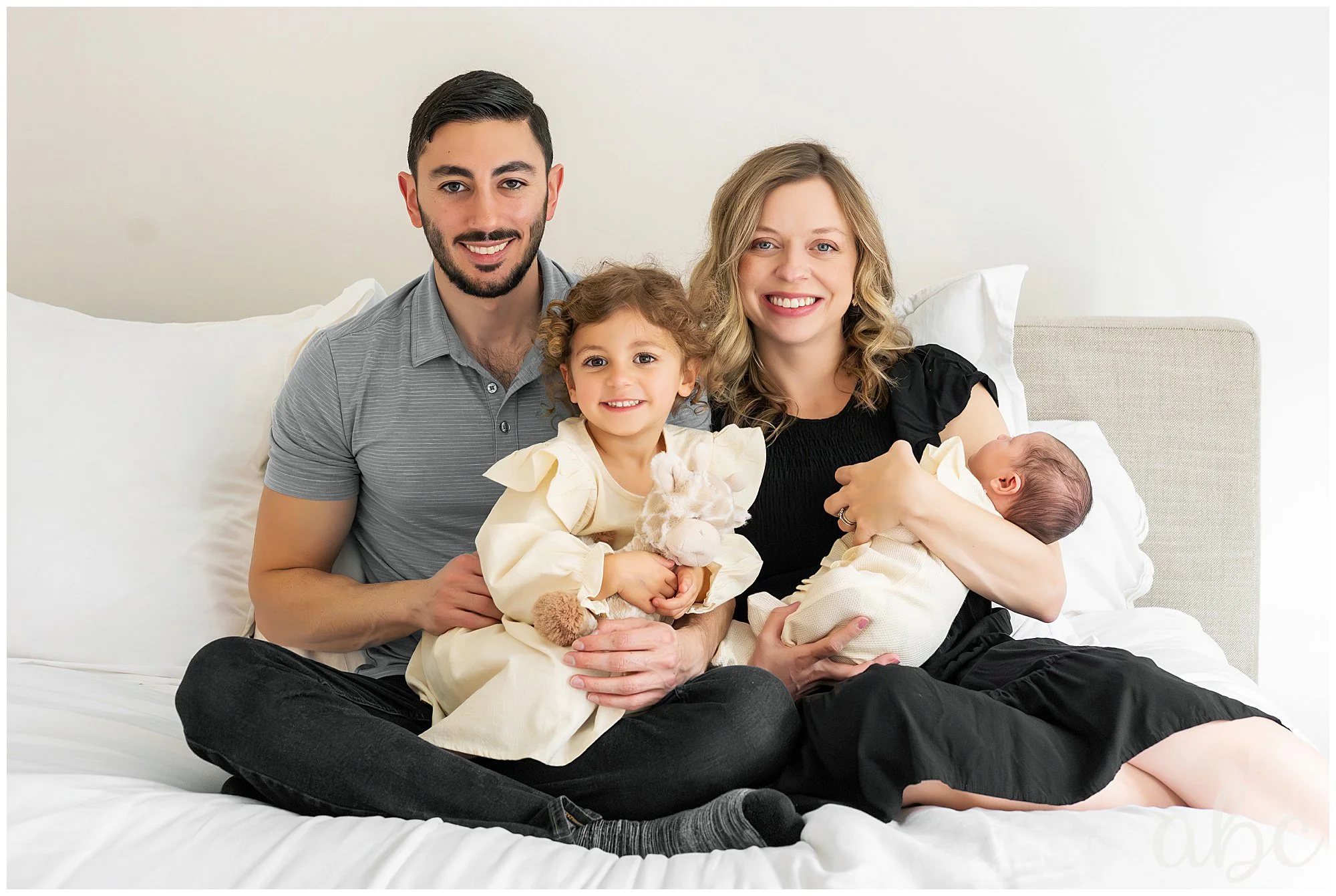 Traditional family poses on the bed while their Roswell doula photographer takes photos