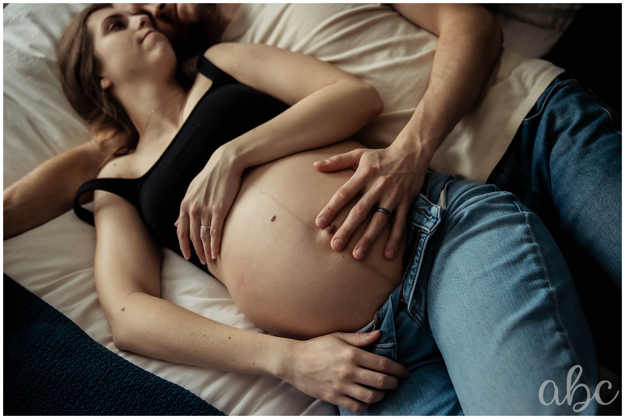 Dad puts his hand on mom's belly to feel the baby kick. Woodstock doula takes a photo