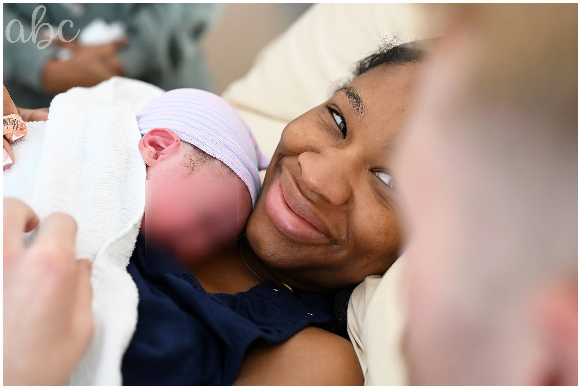 Satisfied mom hugs her new baby and smiles at her partner. Photo by Roswell Doula Maegan Hall