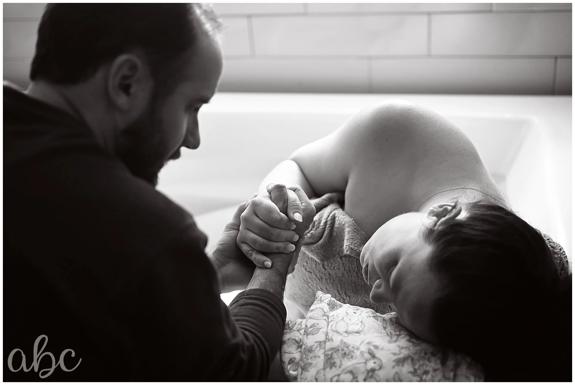 Mom laboring at home in the tub with her Roswell Doula taking photos