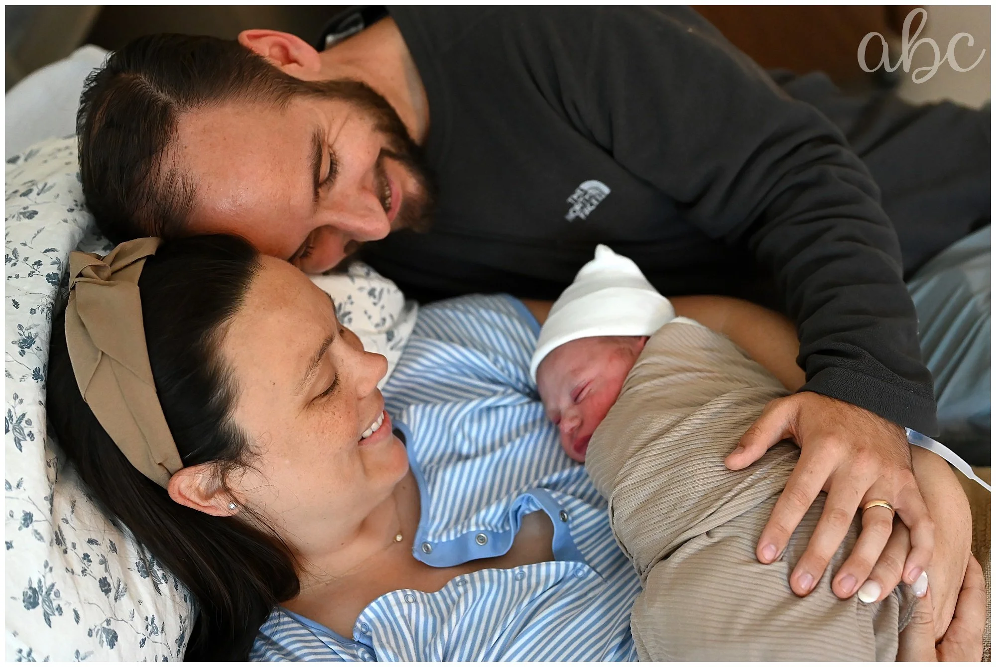 Roswell doula photographer poses couple in the hospital bed with their newborn