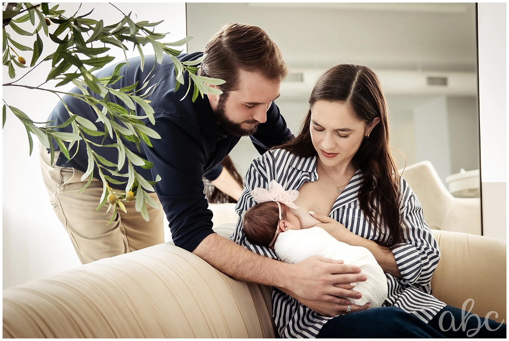 Doula photographer photographs father lovingly supporting wife while breastfeeding