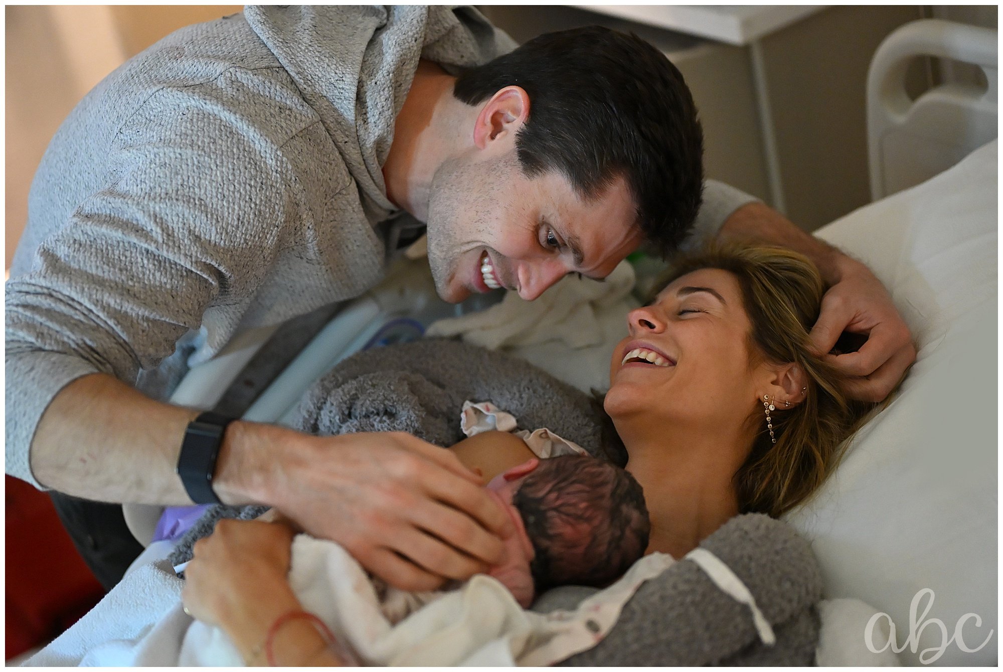 Parents cuddle and laugh from the joy of giving birth with their atlanta doula photographer