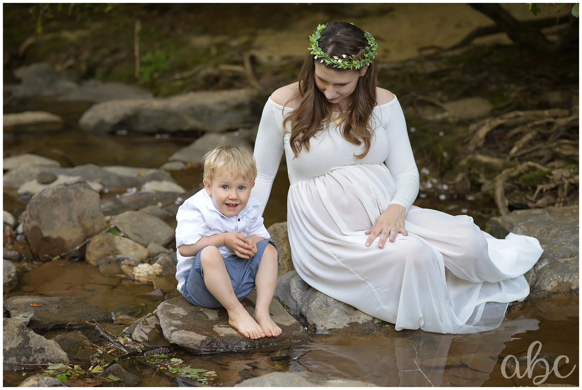 Pregnant woman plays in the creek with her child. Photo taken by Woodstock Doula Photographer