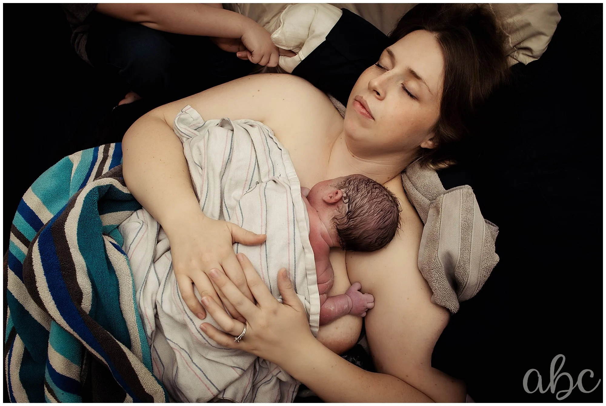 Postpartum mother rests while woodstock birth doula acts as a photographer