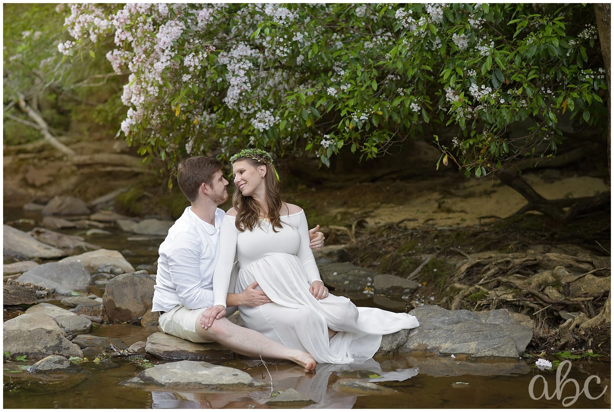 Husband and Wife look at eachother in a beautiful, flowery creek in Marietta