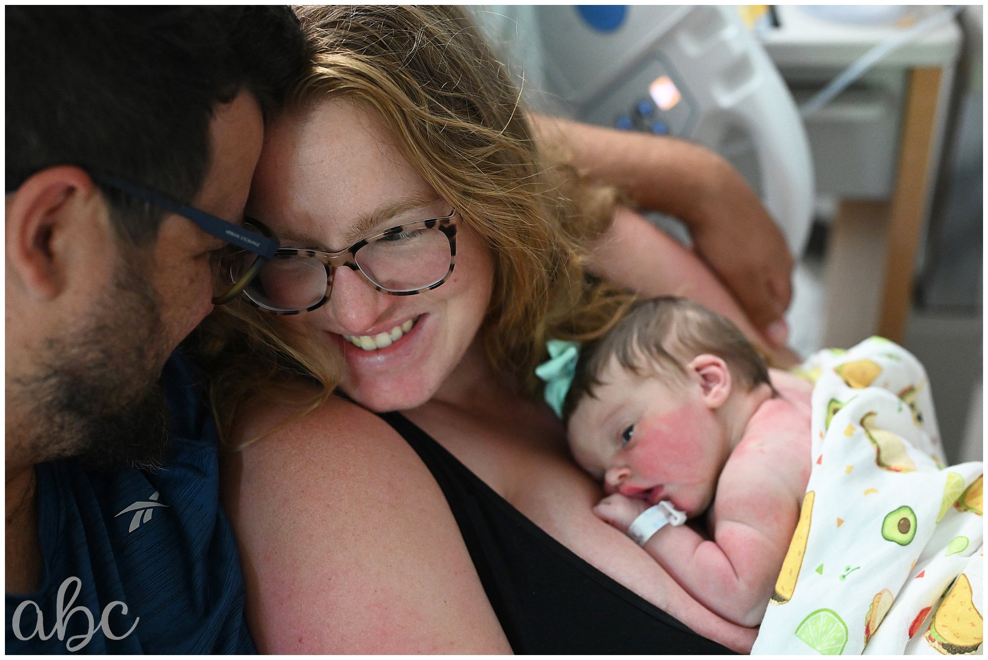 New parents cuddle with their new baby in the hospital.