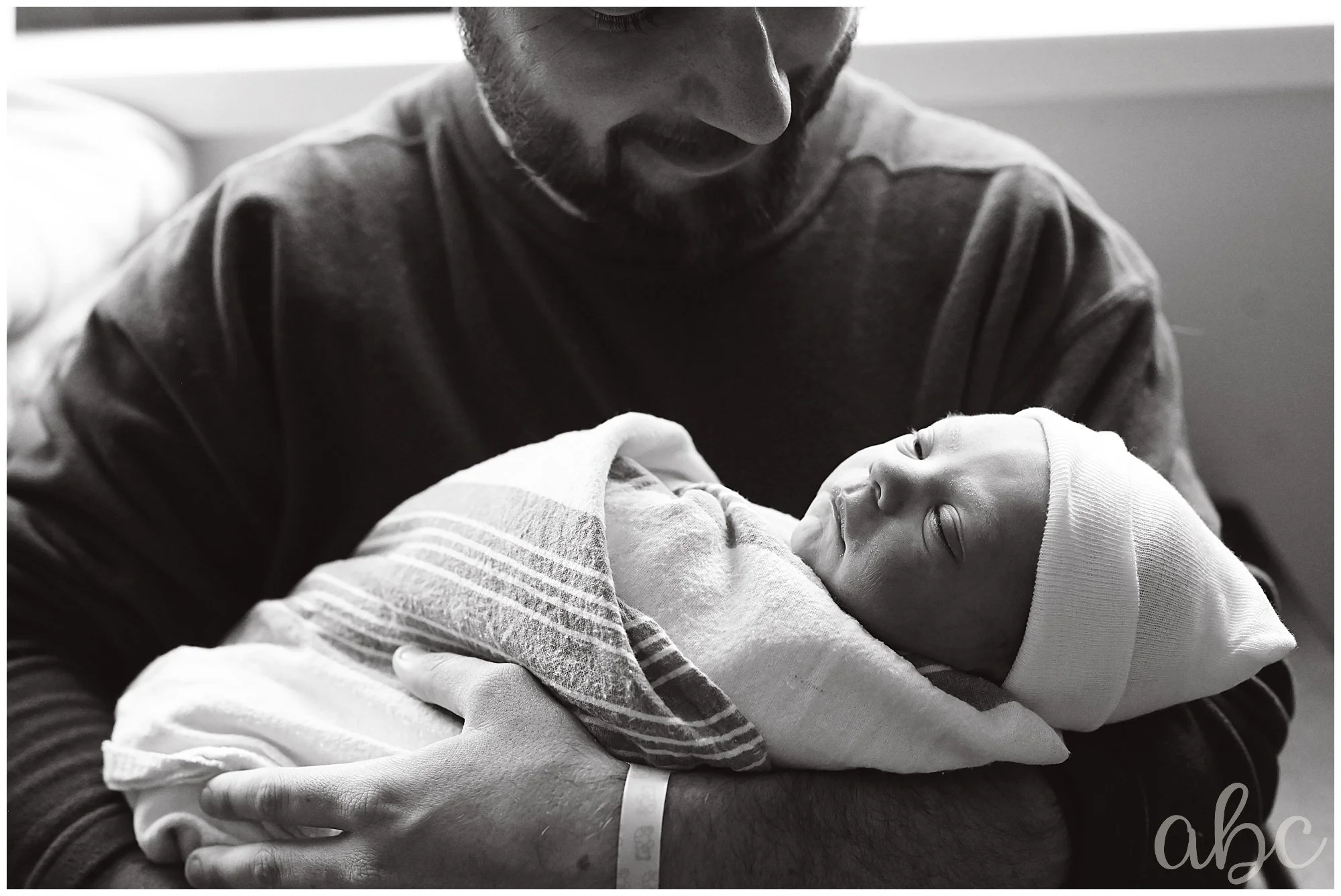 Dad holds newborn in the hospital as labor doula takes photos