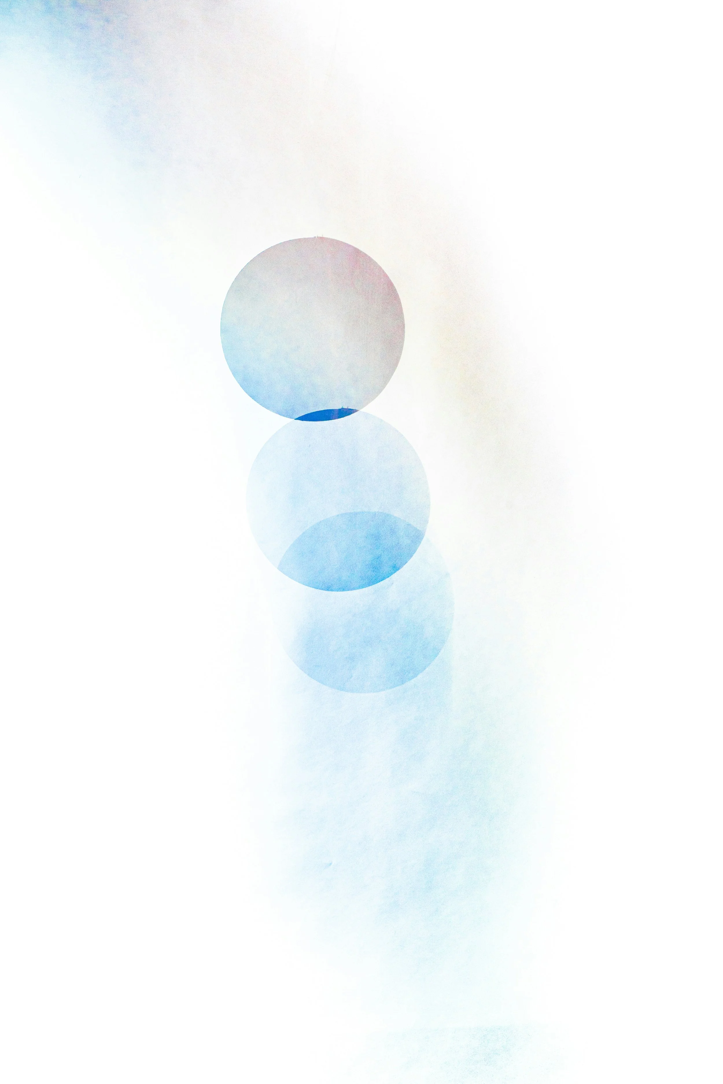 Abstract image with a vertical arrangement of semi-transparent blue and purple circles on a white background.