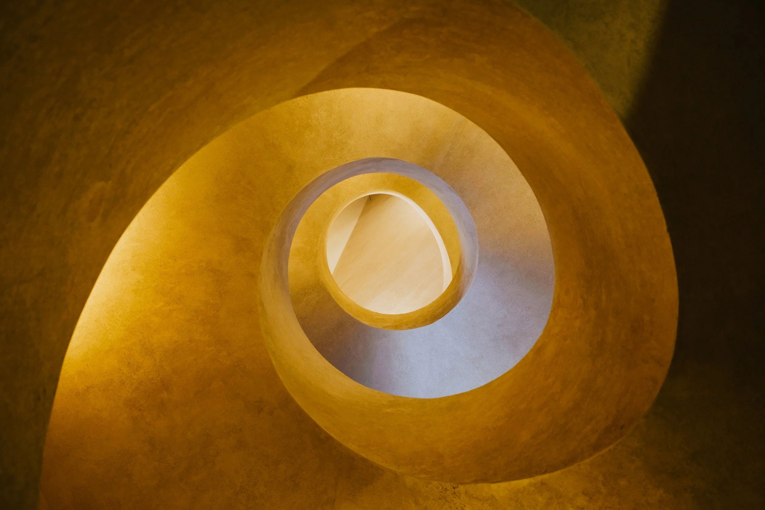View looking up inside a spiral staircase with yellow walls.