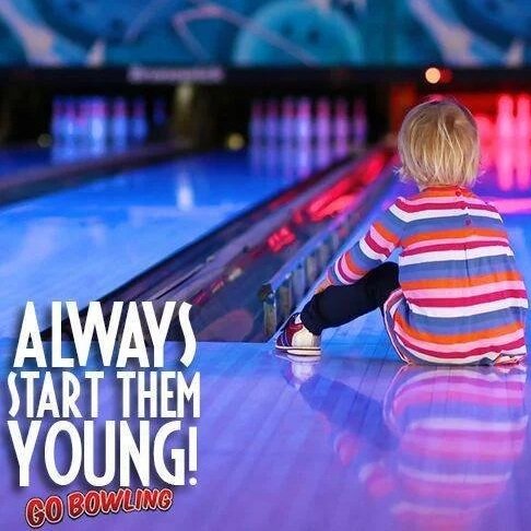 A young child with blonde hair, wearing a colorful striped shirt, sitting on the floor of a bowling alley next to a bowling lane, with bowling balls and pins visible in the background. The image includes the text "Always Start Them Young!" and "Go Bowling."