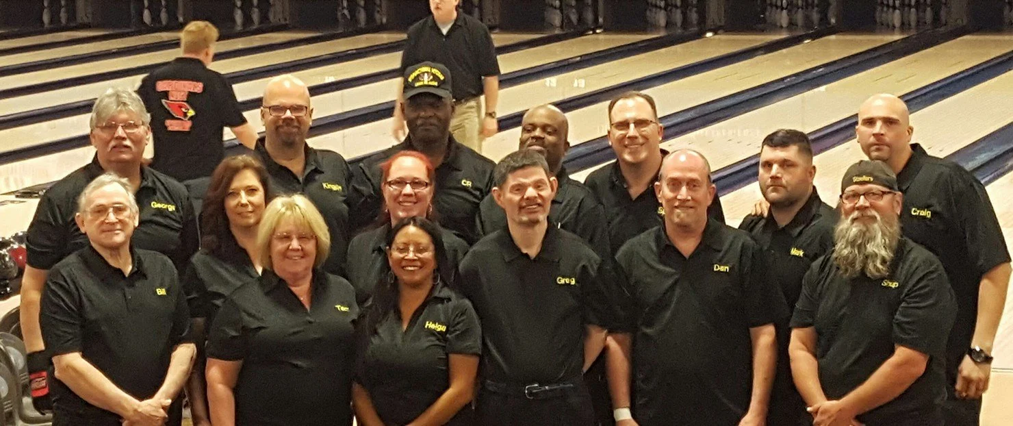 Scott Gielda's National Team  of people wearing black shirts with embroidered names, standing in a bowling alley.