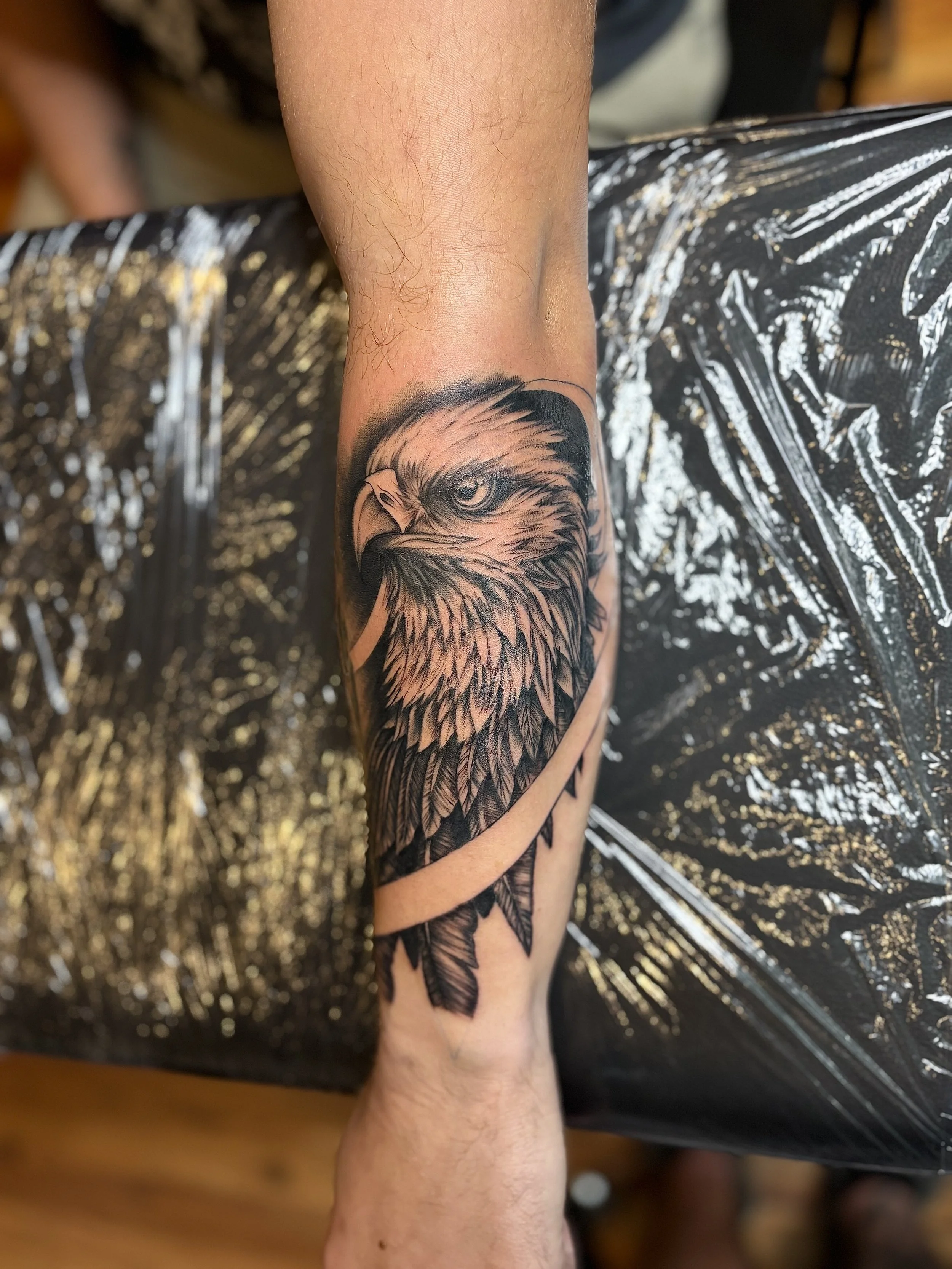 Black and grey tattoo of an eagle's head on a person's arm.