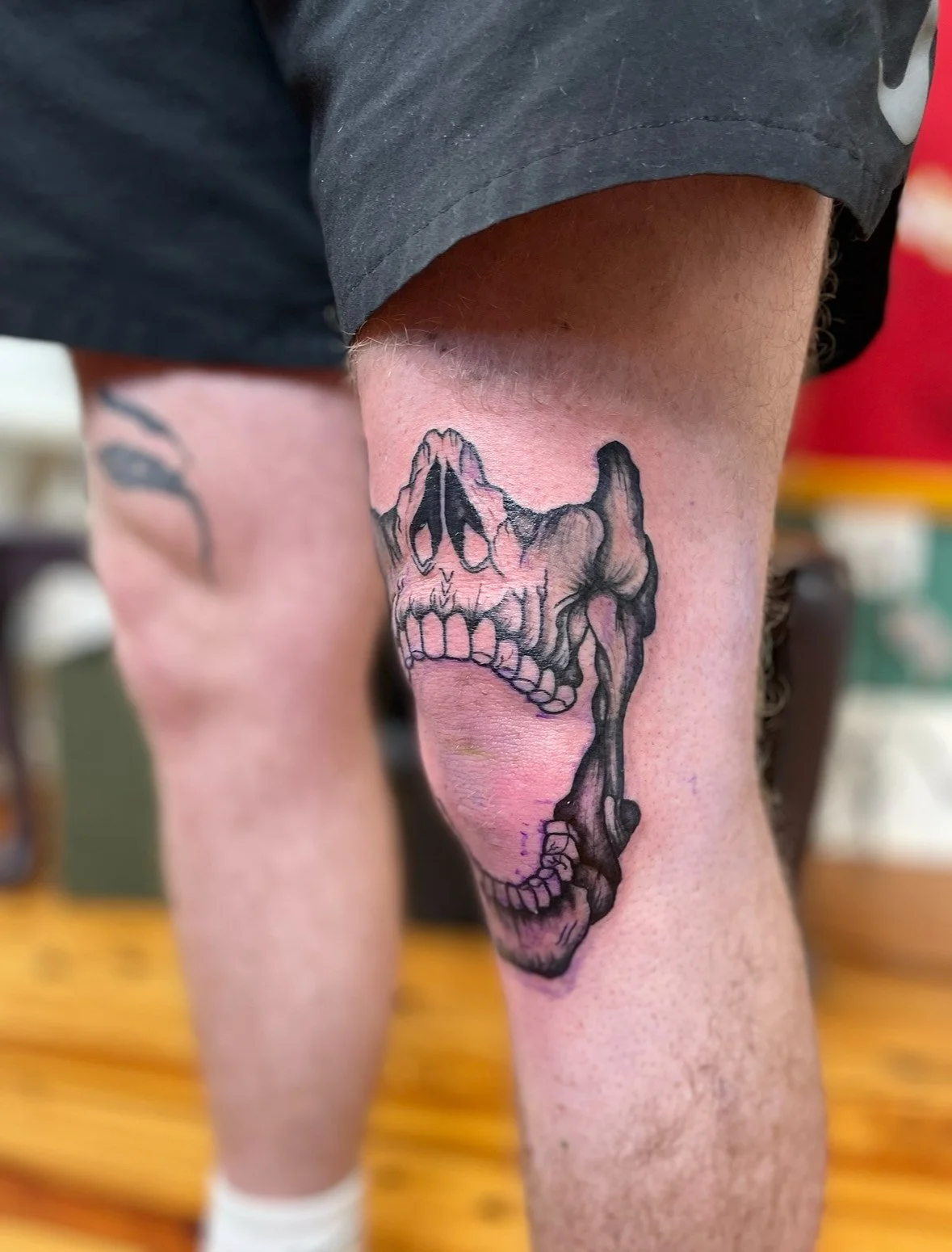 Tattoo of a skull with brain and mountain design on a person's thigh.