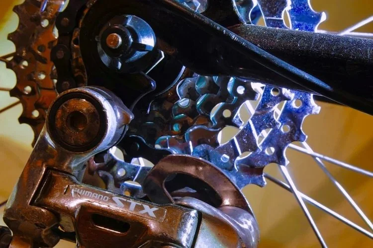 Close-up of a bicycle's gear cassette, derailleur, and chain.