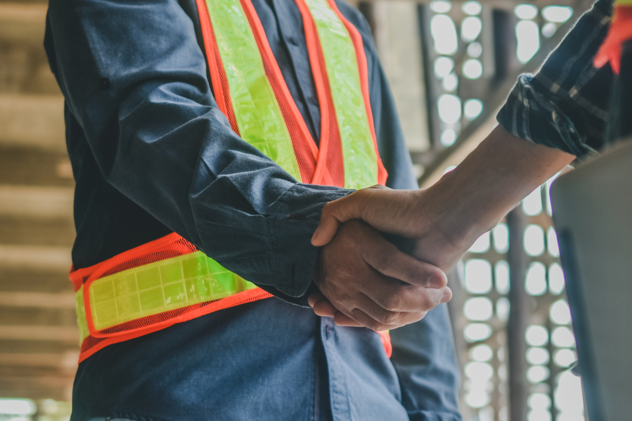 Construction workers shaking hands to standardize SOPs and improve operational consistency.