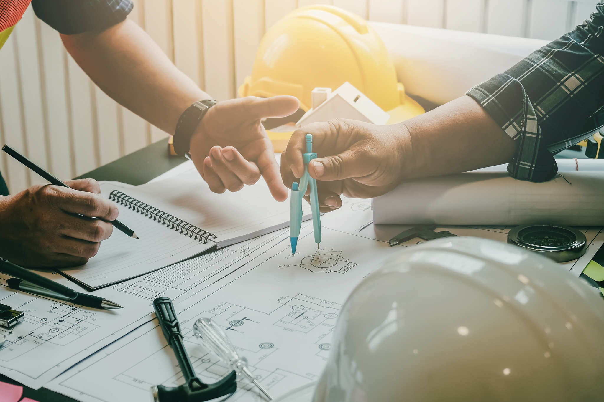 Construction managers analyzing blueprints and project data to improve forecast accuracy through better financial systems and job tracking.