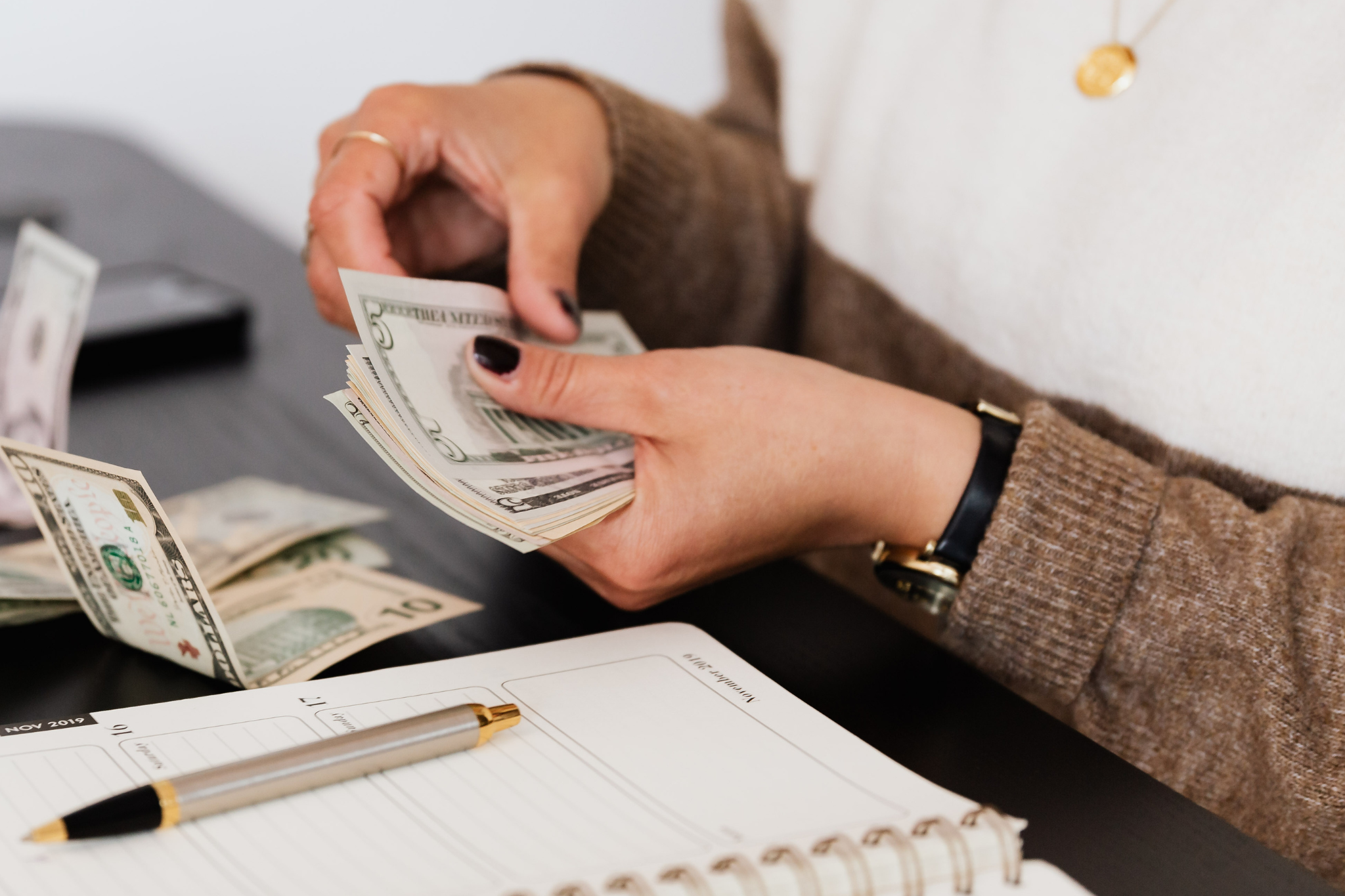 Construction business owner counting cash and reviewing finances while tracking project costs, job profitability, cash flow, and budget performance to improve construction accounting and financial visibility.