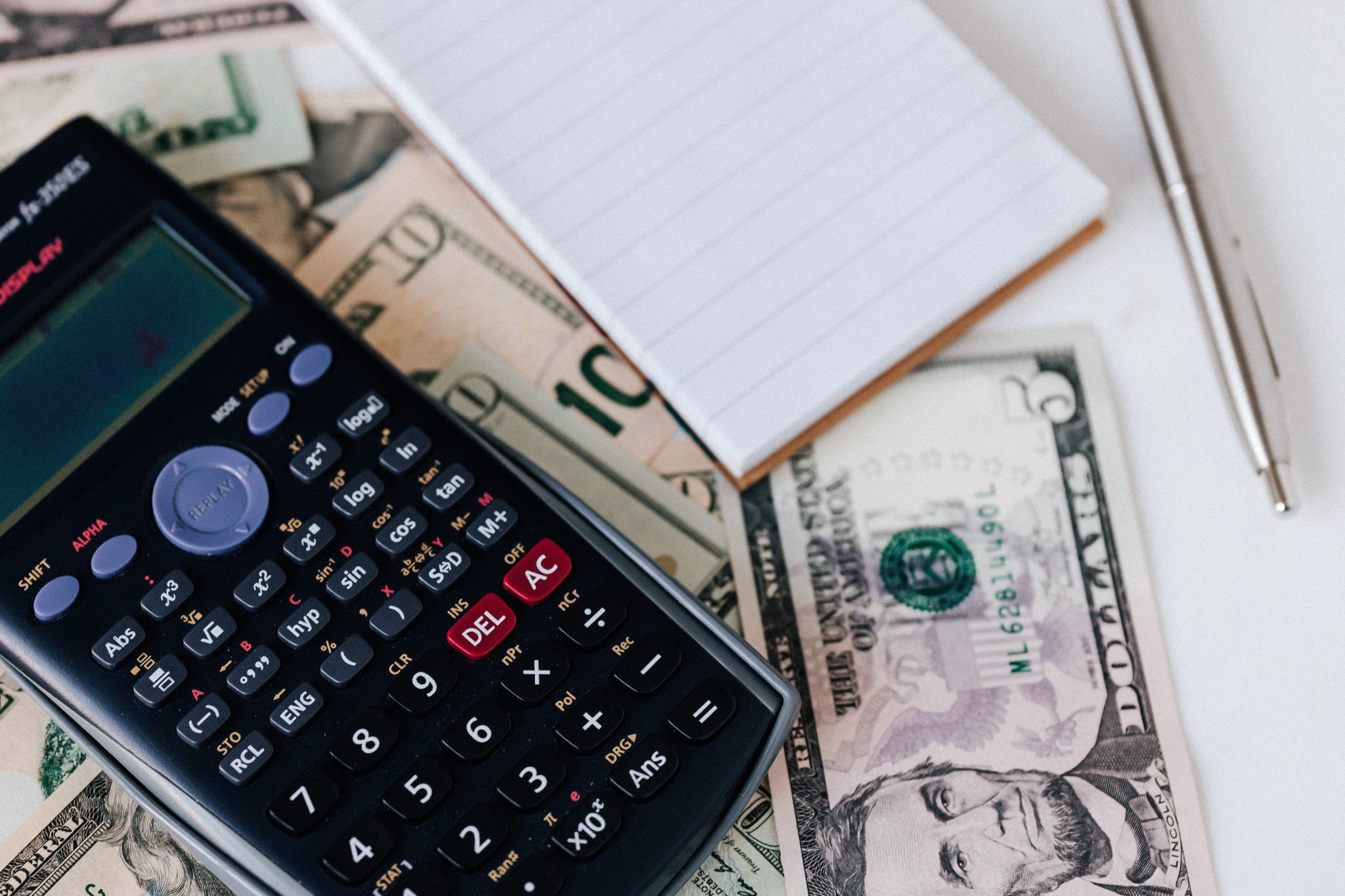 Calculator, cash, notebook, and pen symbolizing construction business finances. Rapid contractor growth often exposes weaknesses in bookkeeping, job costing, cash flow management, and financial systems that were sufficient at a smaller scale.