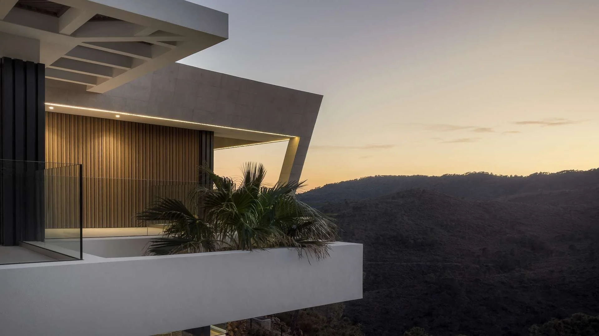 Modern building with geometric architecture overlooking hills at sunset