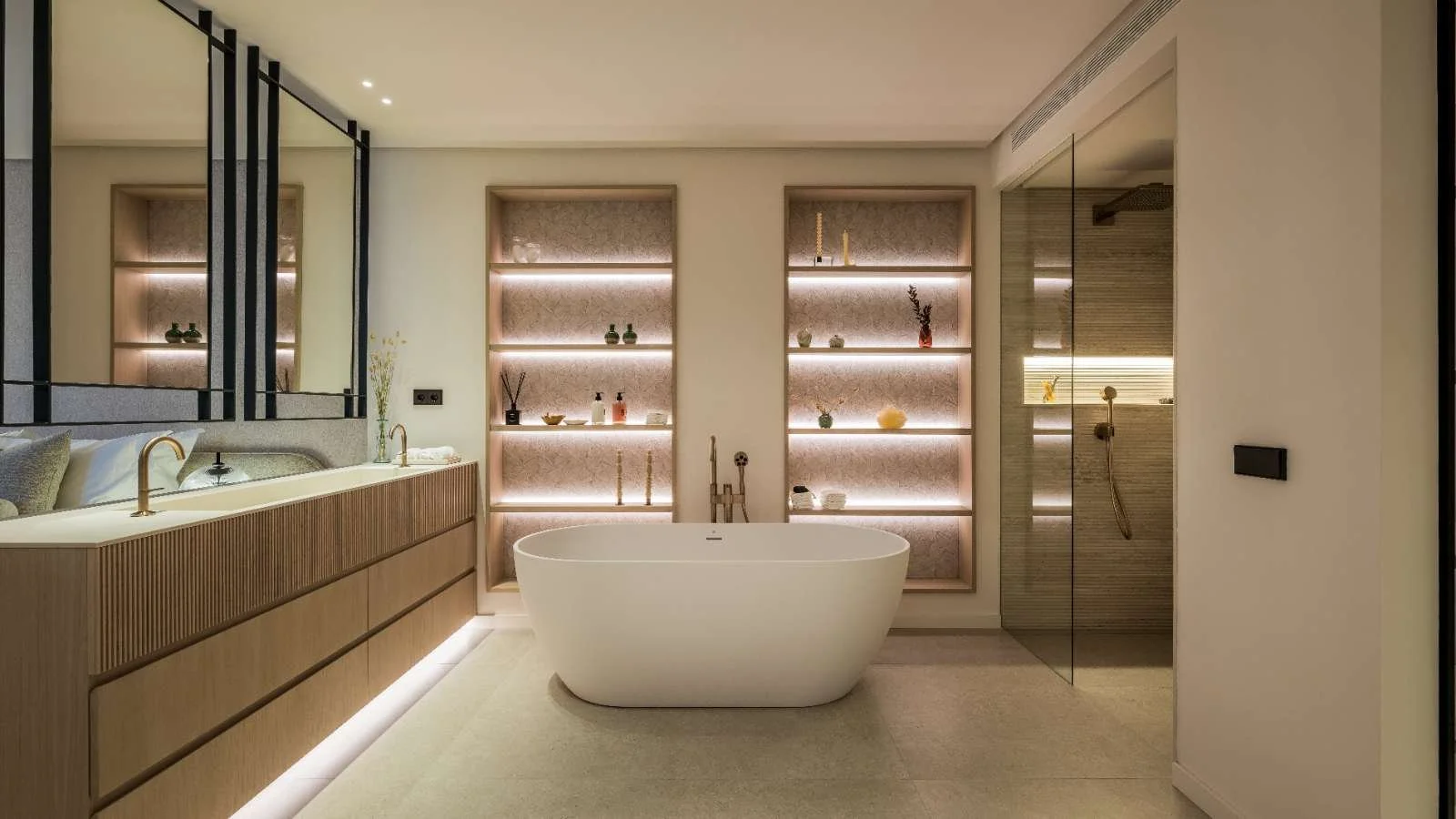 Modern bathroom with freestanding bathtub, glass shower, shelving with decorative items, and minimalist design.