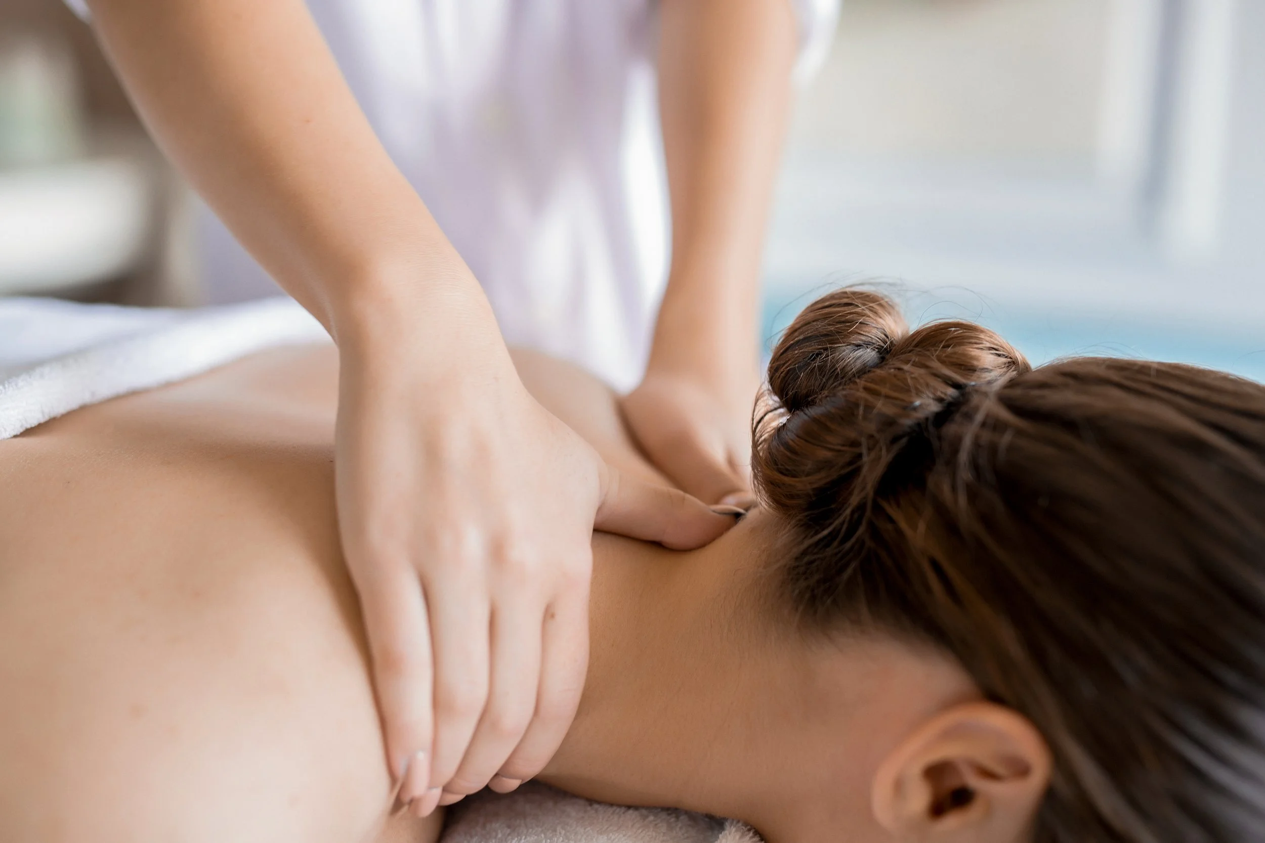 A person receiving a massage on the back from a massage therapist in a spa setting.