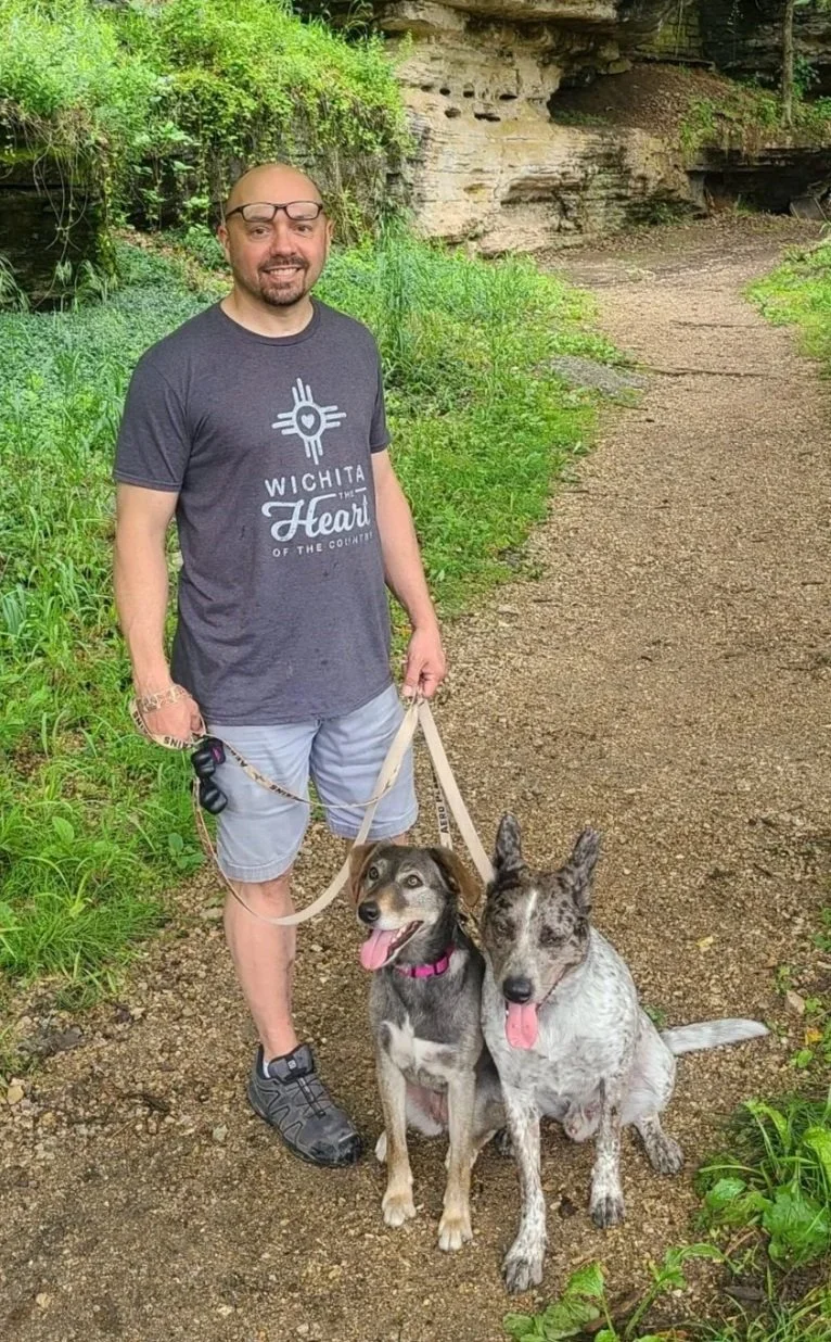 Lance with two dogs, on a trail wearing "Wichita" shirt