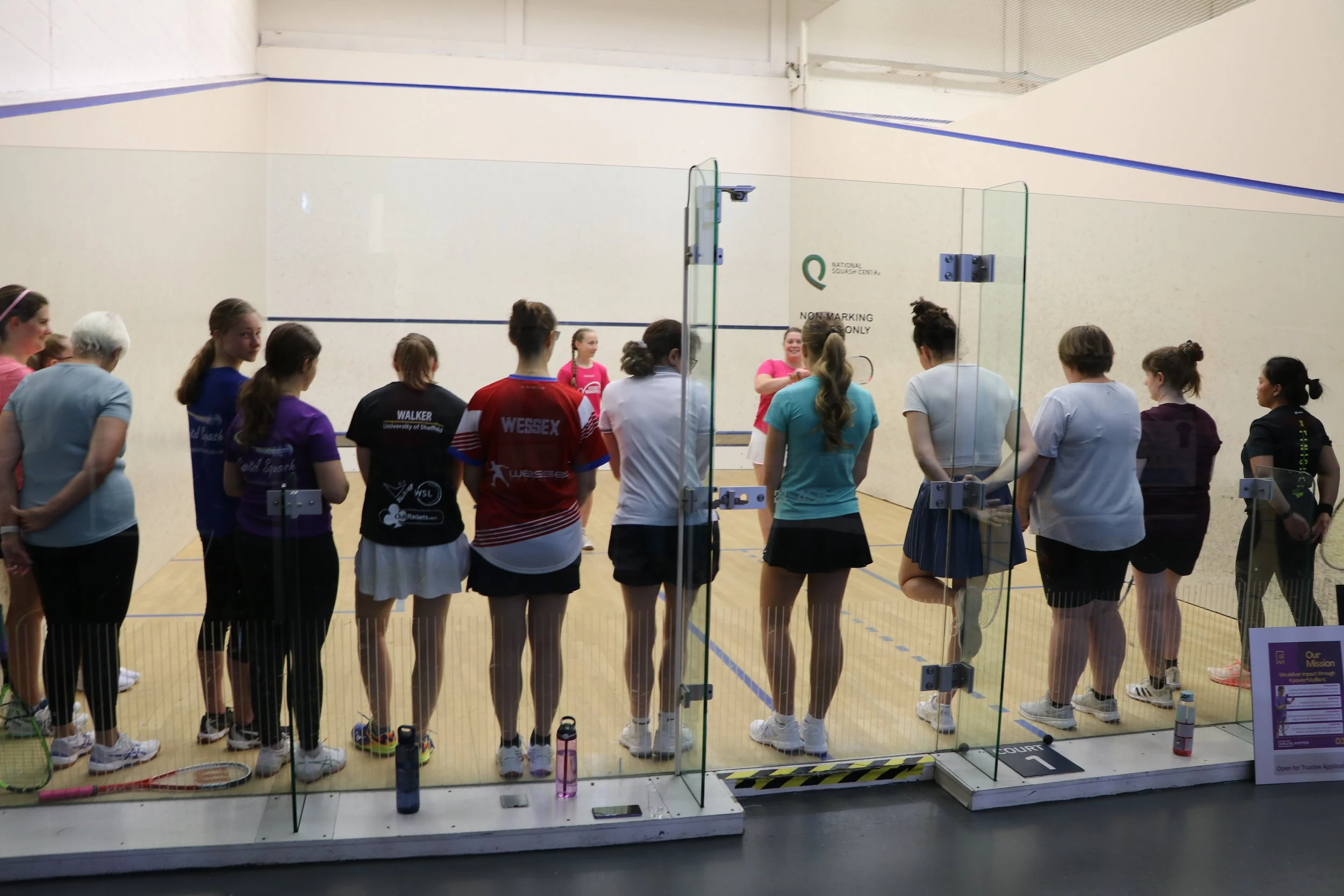 Female squash coaches leading a group of women on court in a community event