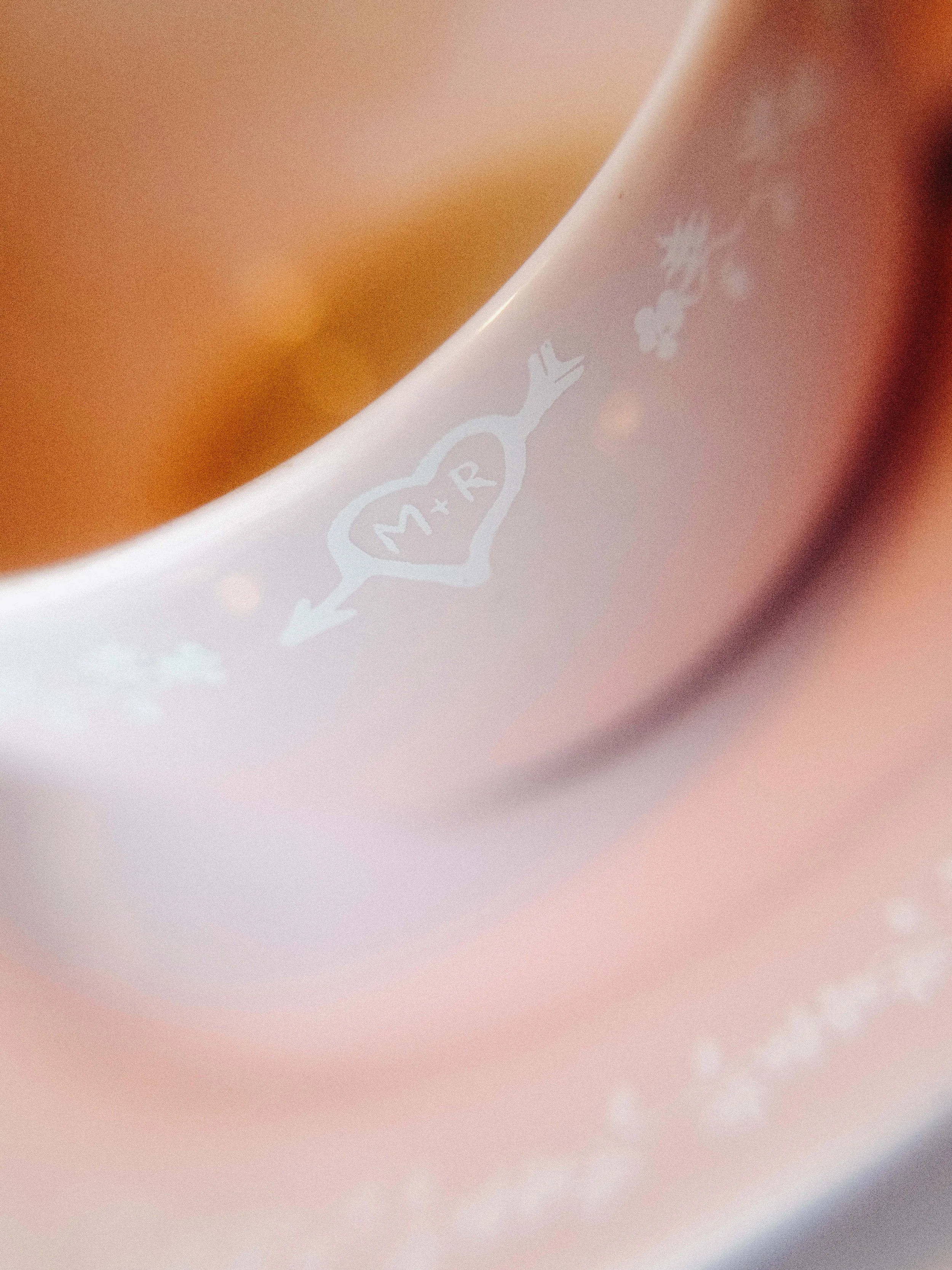 Gobelet en papier blanc avec des illustrations de petits flocons de neige et un cœur avec une flèche à travers, contenant une boisson chaude.