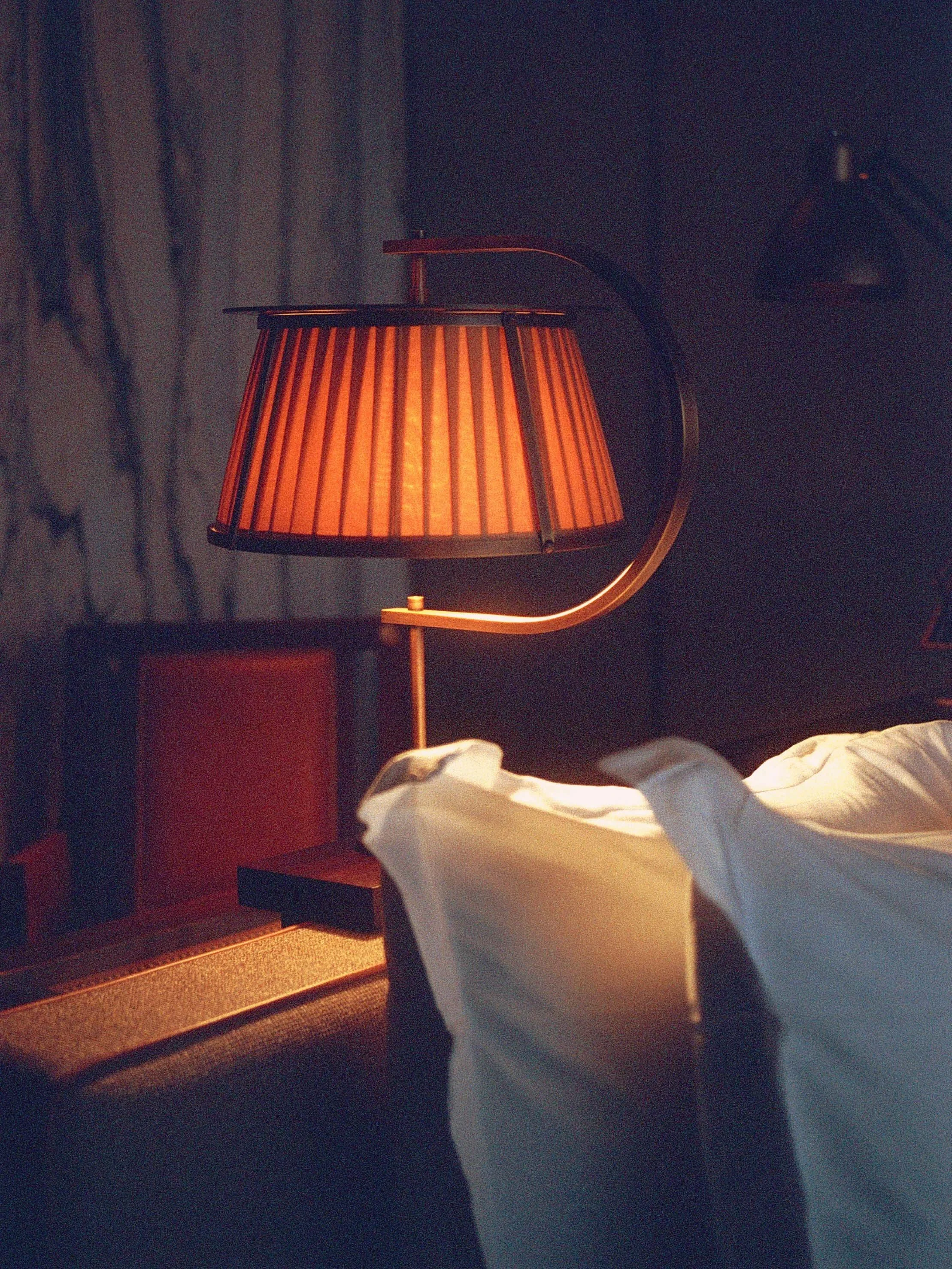Lampe de chevet allumée à côté d'un lit dans une chambre d'hotel