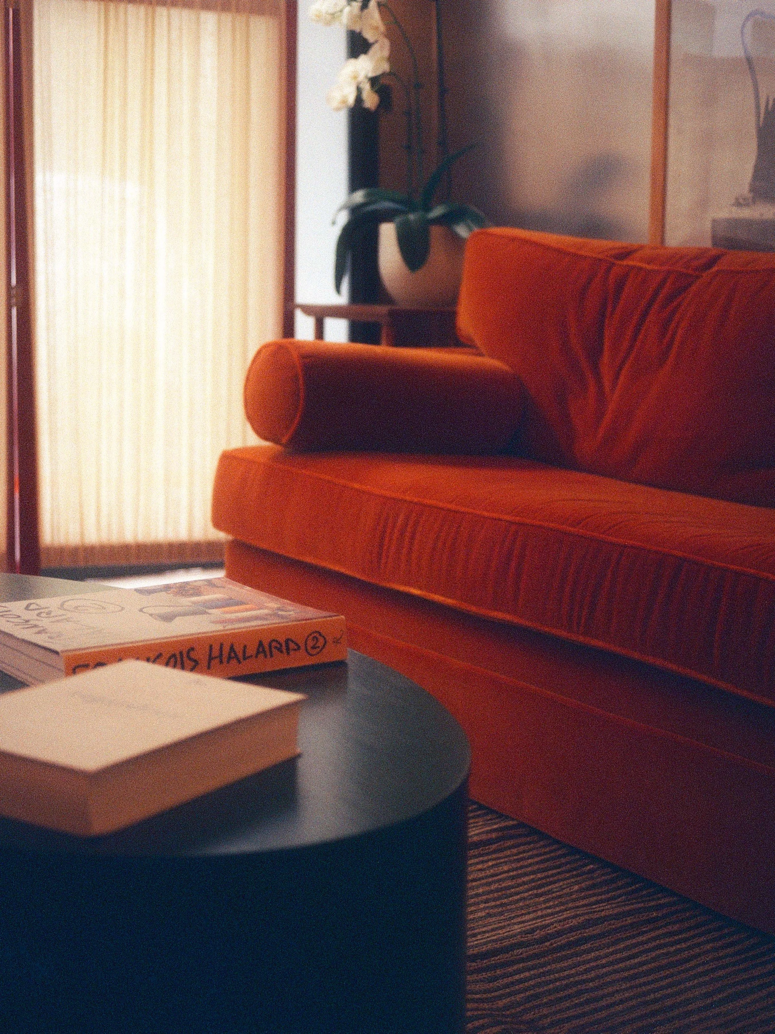 Salon d'un hotel Parisien avec un canapé orange, une table basse avec des livres