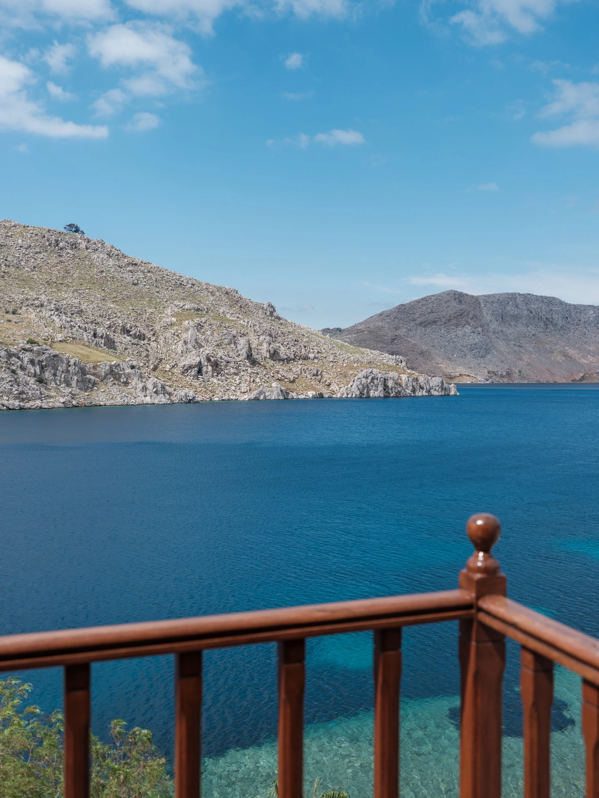 Eos suite balcony overlooking nimborio bay with rocky hills under a blue sky at the selene greece, symi