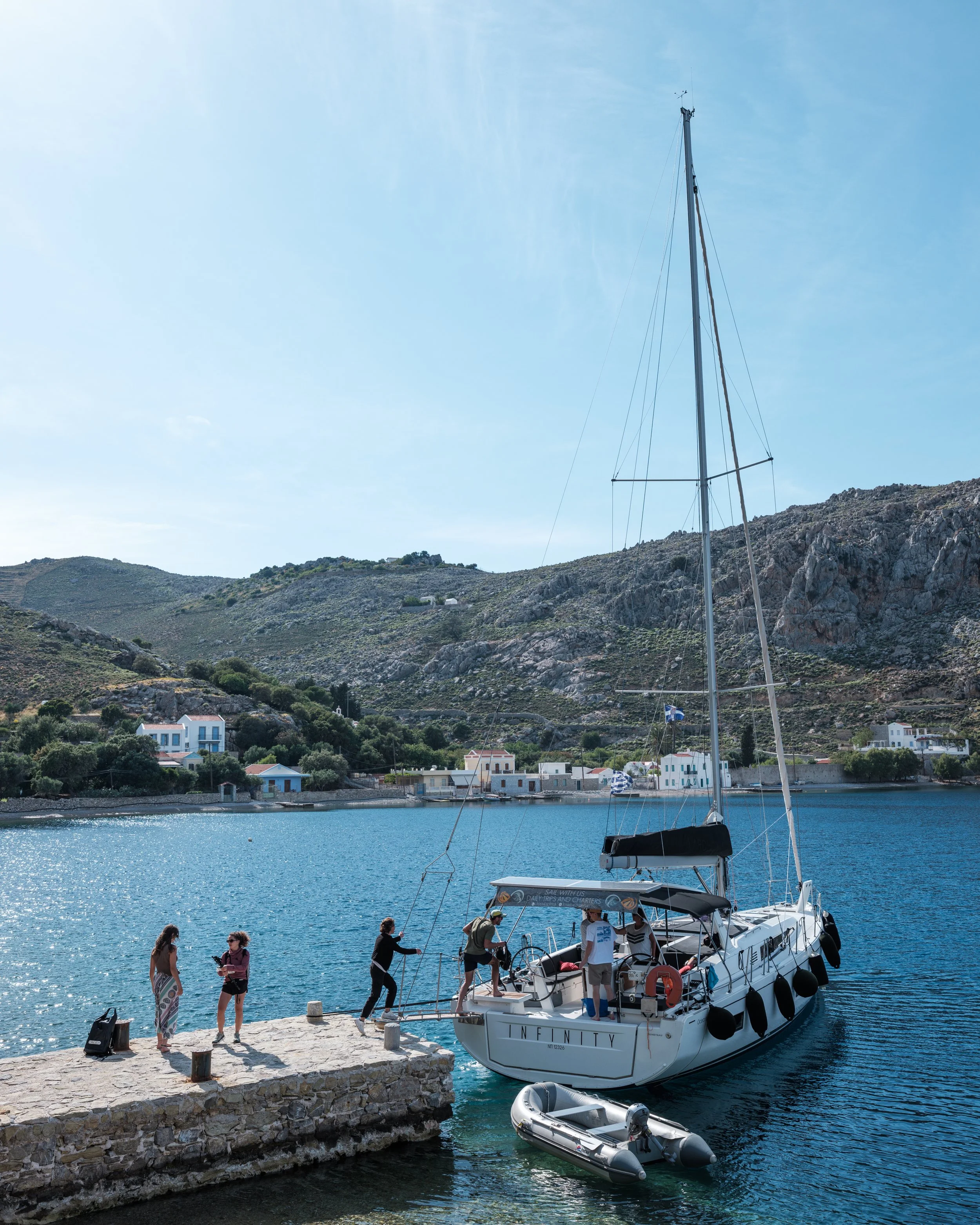 Sailboat Infinity dropping guests off at the dock in Nimborio bay, directly in front of Selene Greece Symi