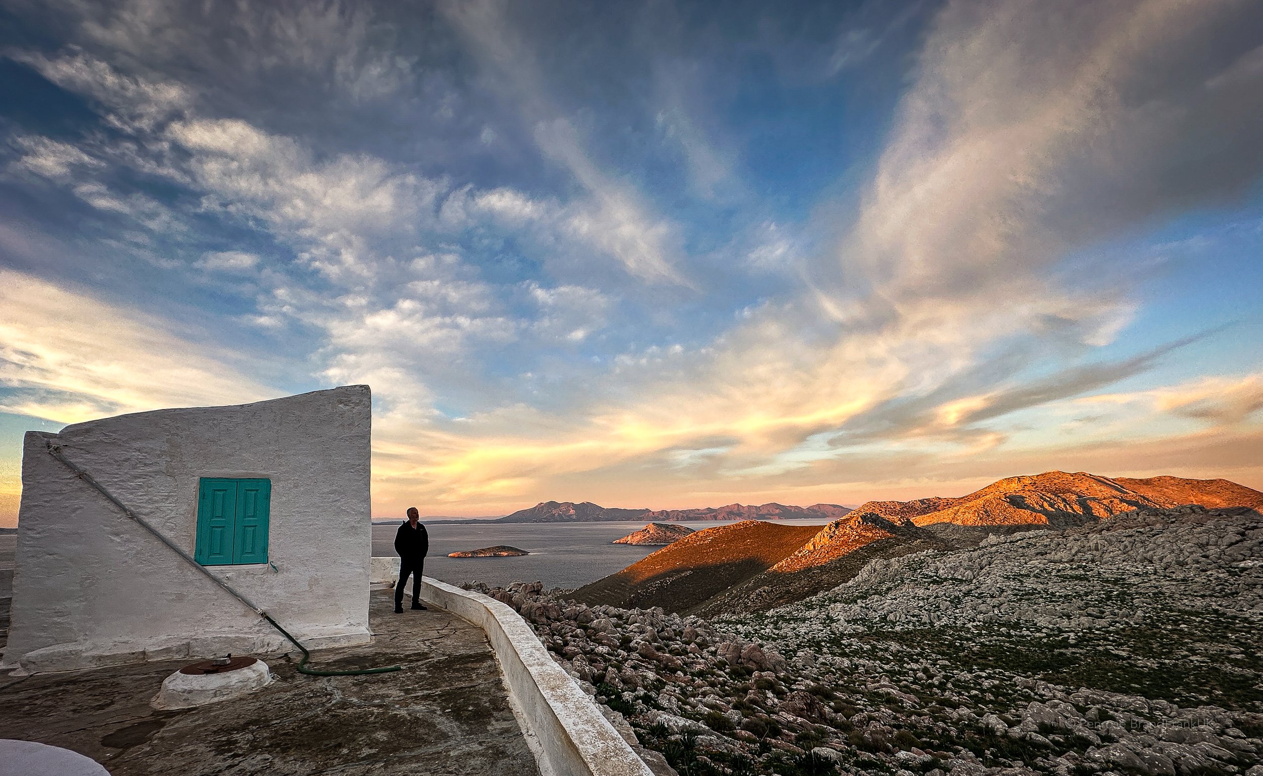 At St Nikolas church on Symi Greece. Overlooking a rocky landscape and Aegean Sea with mountains in the background during a sunset or sunrise.