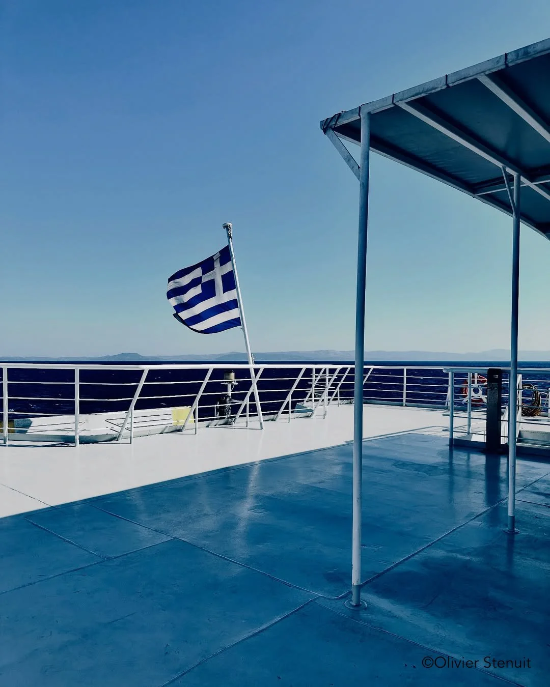View of the deck on a ferry crossing to Symi Greece from Rhodes. Flying the Greek flag, and a blue sky in the background.