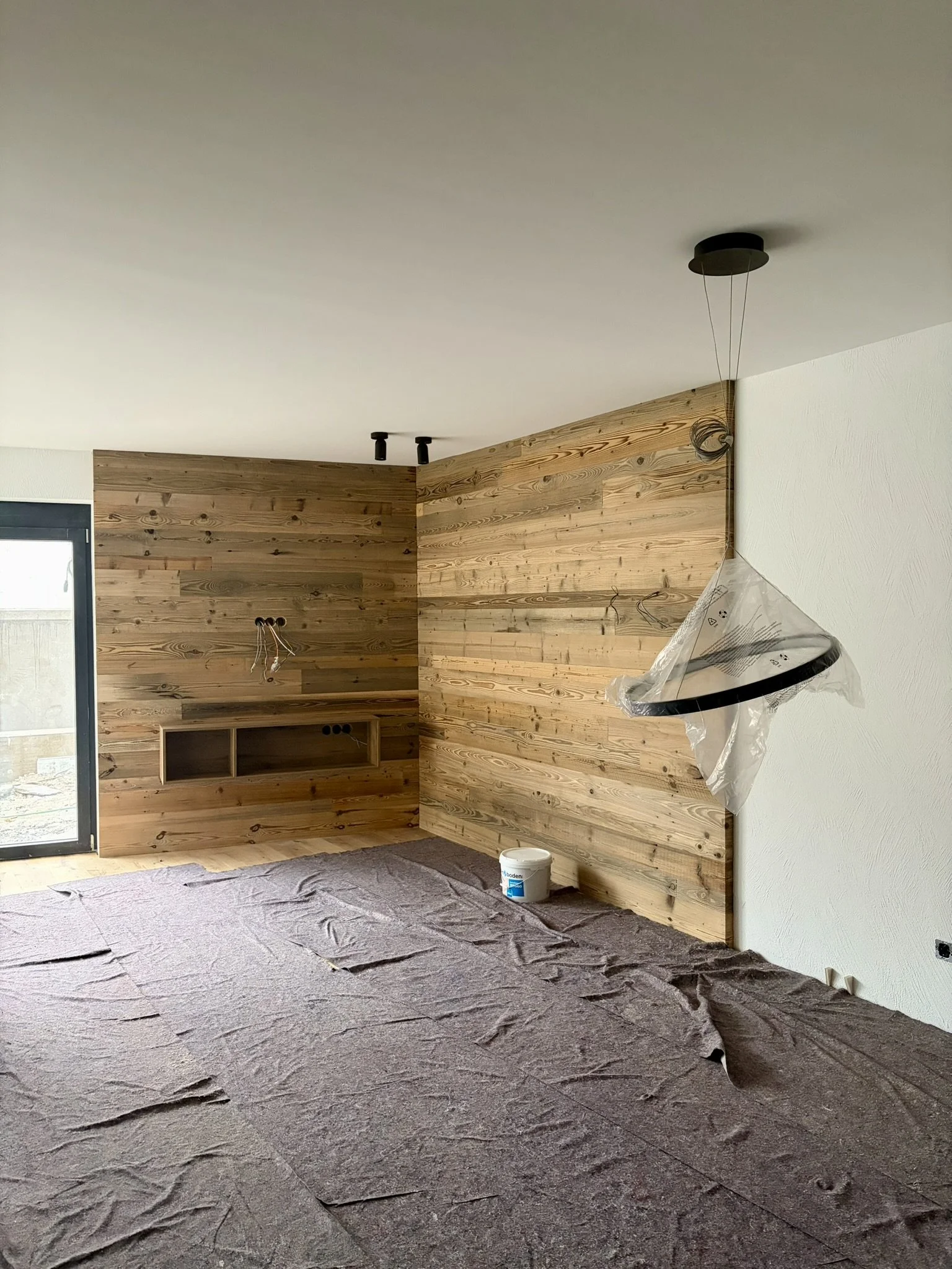 Wohnzimmer mit Altholzwand und Medienfach im Endausbau