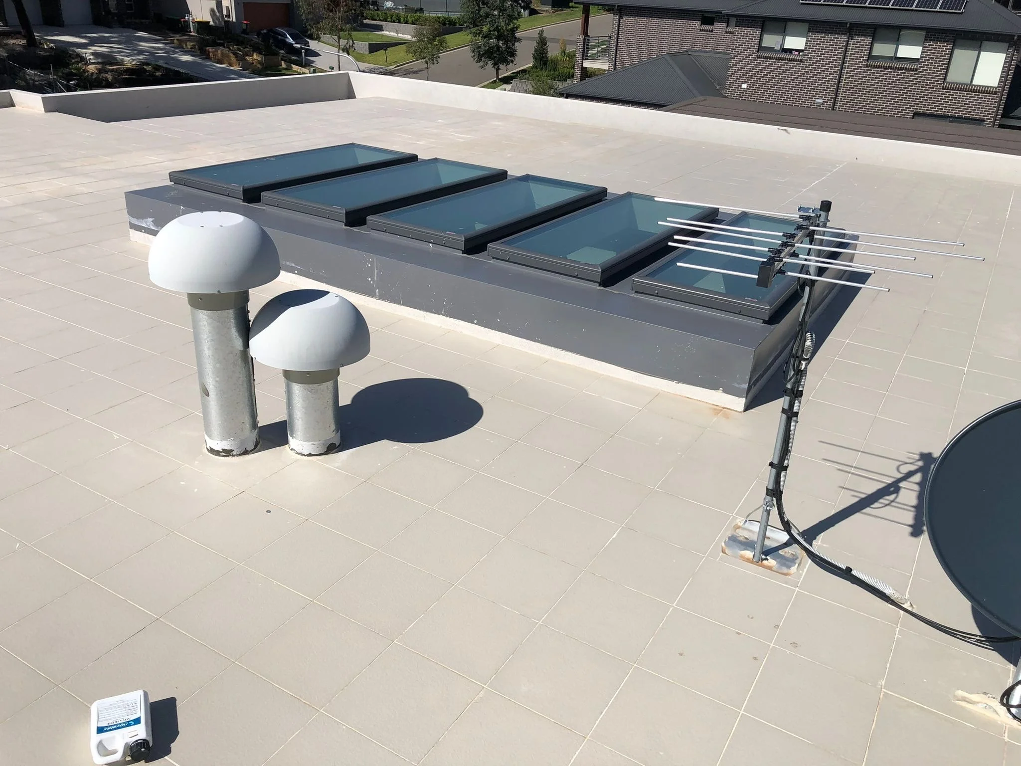 Rooftop with skylights, two vent pipes, and a satellite dish antenna.