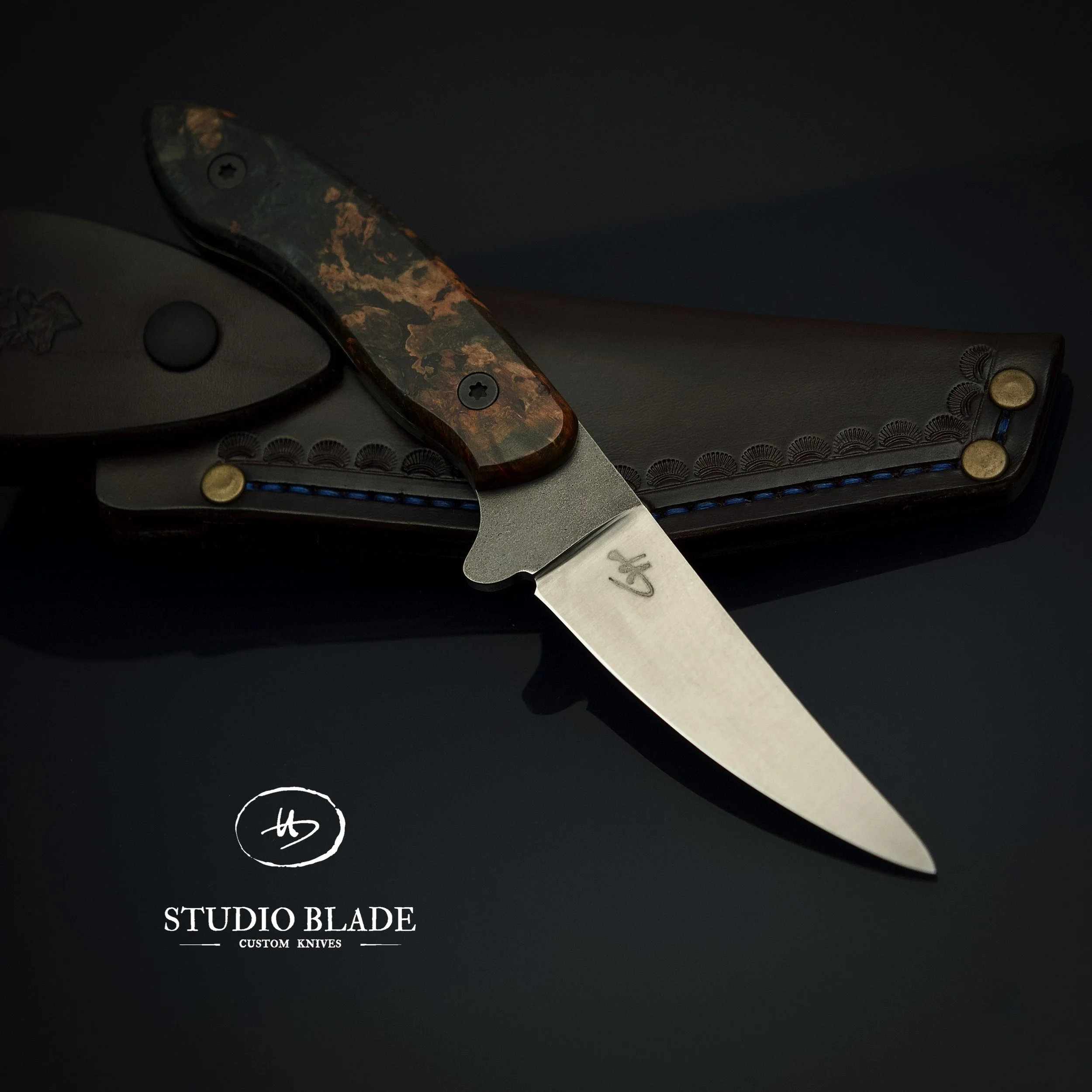 A custom Hubert hunter full tang knife made by Stuio Blade in Switzerland, featuring a stabilised Walnut burl handle and an Magnacut steel blade, placed on a black surface with the logo 'Studio Blade' and the text 'Custom Knives' underneath.