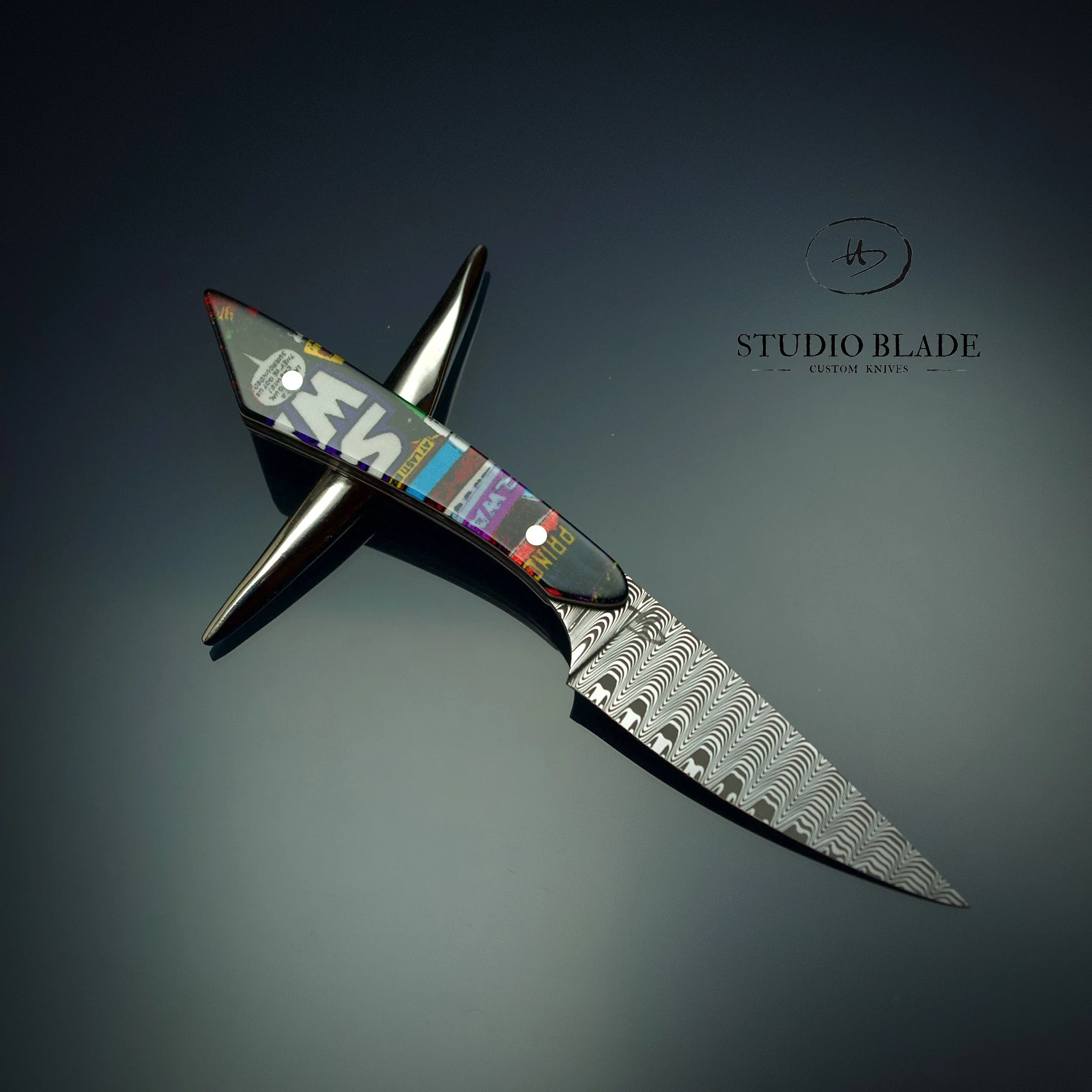 A custom culinary knife with a stainless damascus blade and a handle covered in colorful, graffiti-style Star Wars art cartoon, positioned against a dark background with 'Studio Blade Custom Knives' logo in the upper right corner.