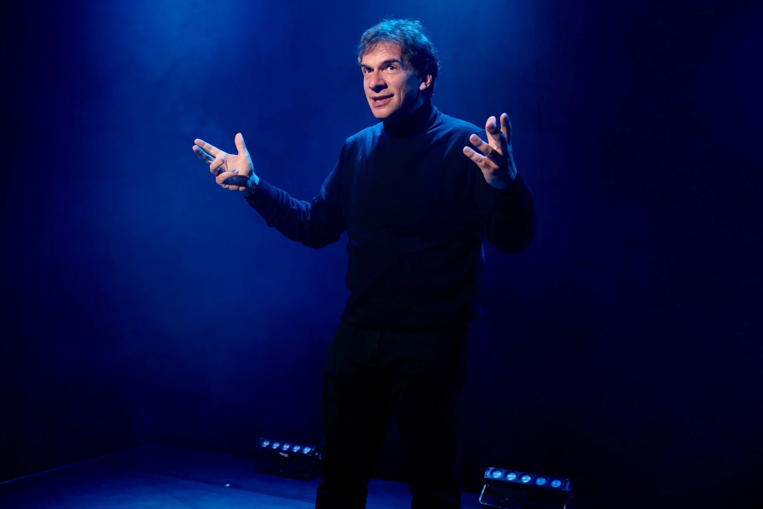 Pierre Diot sur scène, avec un éclairage bleu foncé.