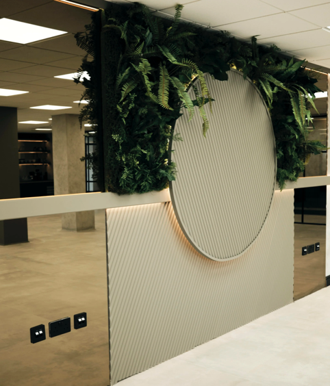 Interior office space featuring a decorative wall with artificial hanging plants and a circular design element.