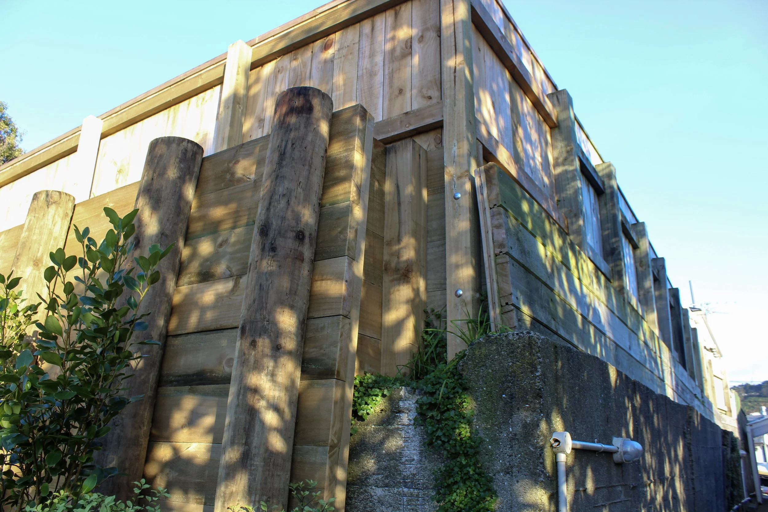 The new timber retaining walls tying in with the existing concrete wall, constructed separately to avoid bearing more weight on it.