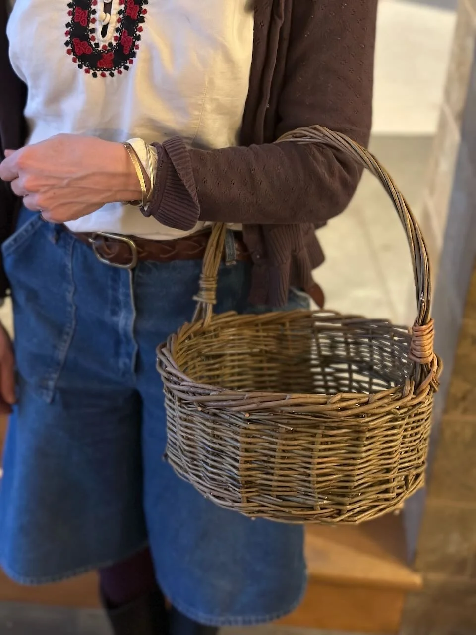 A person is holding a wicker basket with a handle.