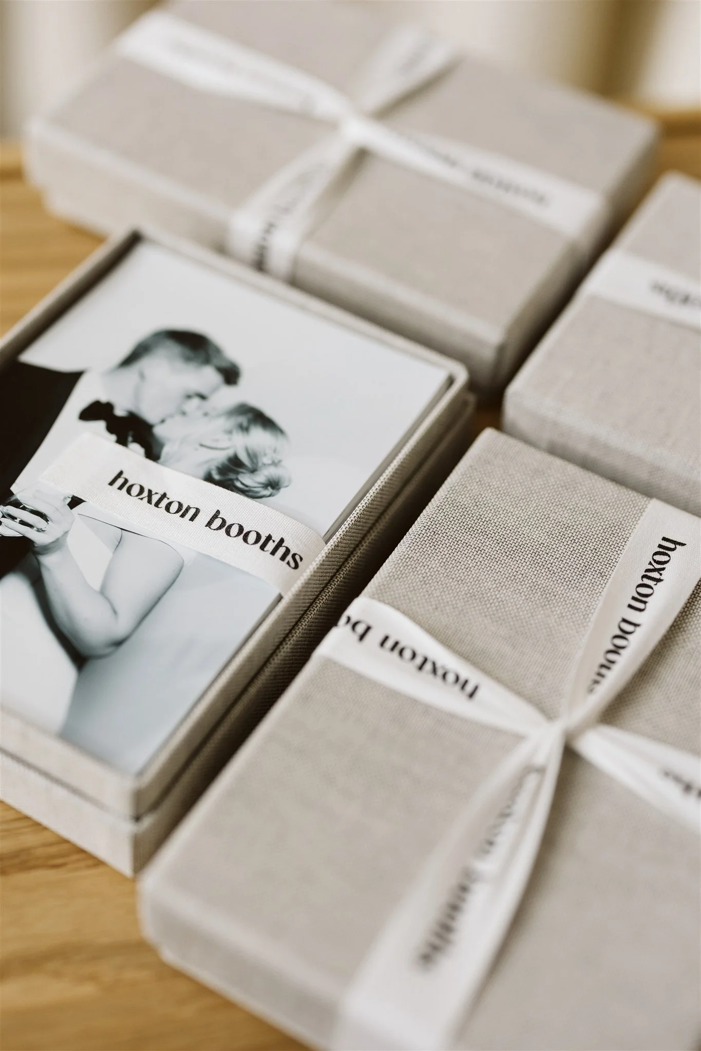 Boxes of black and white photo prints with a label reading 'Hoxton Booths' on a wooden surface.