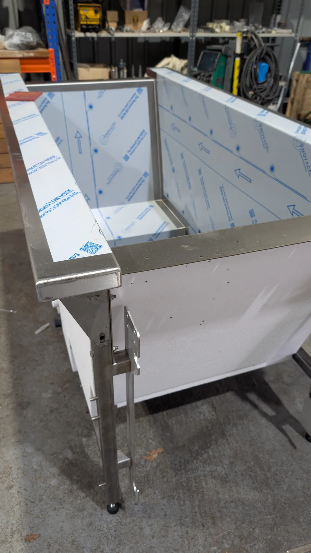 A stainless steel tub shell with protective film, mid-build.